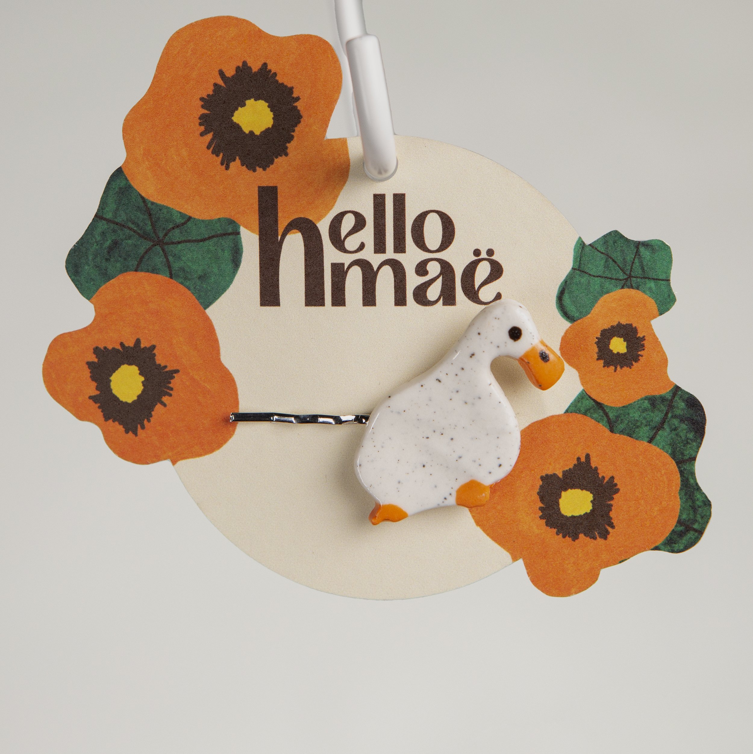 Handmade ceramic hair pin with a glossy dreamer white duck, photographed on a neutral background.