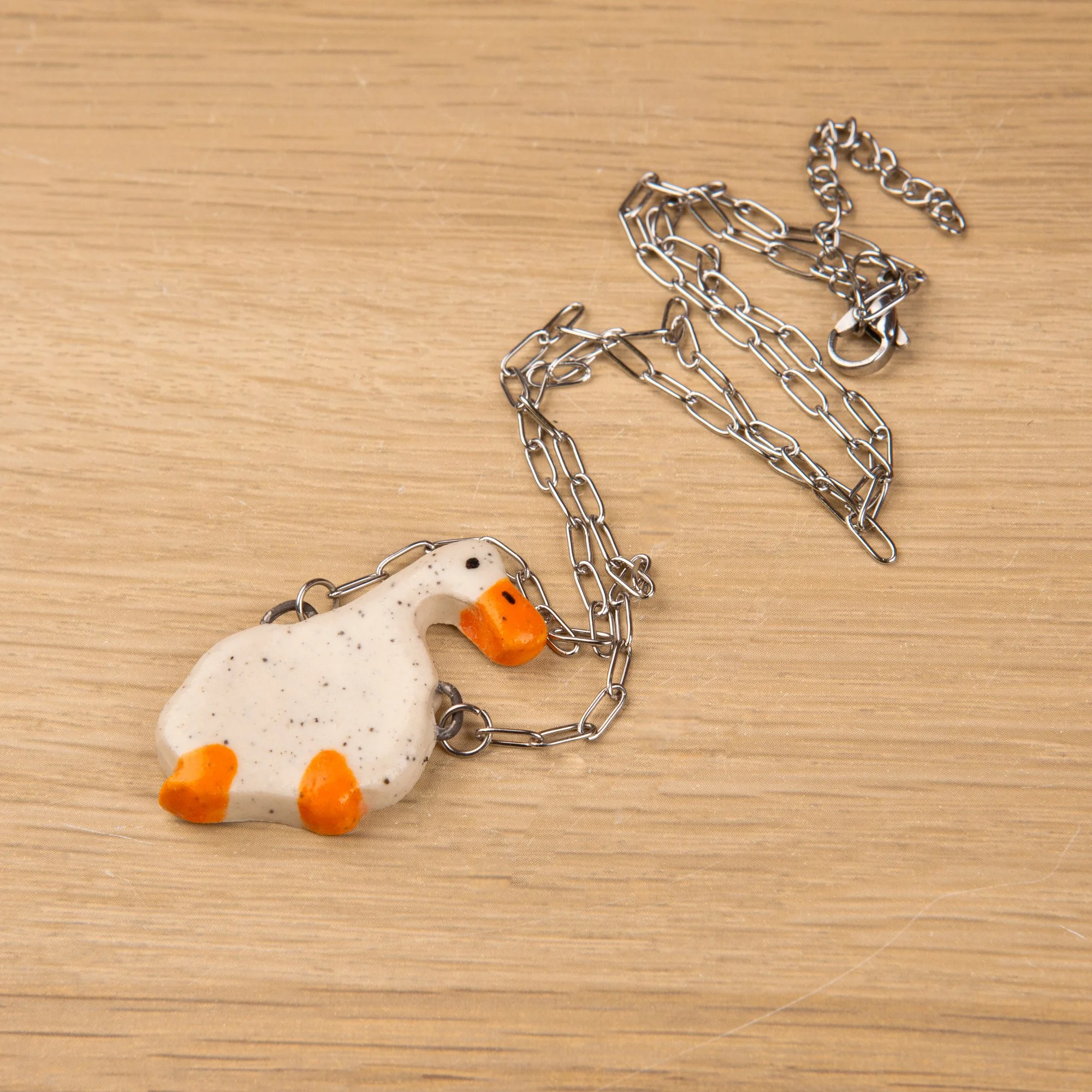 Handmade ceramic duck necklace featuring a playful hand-painted duck pendant on a silver-coloured chain.
