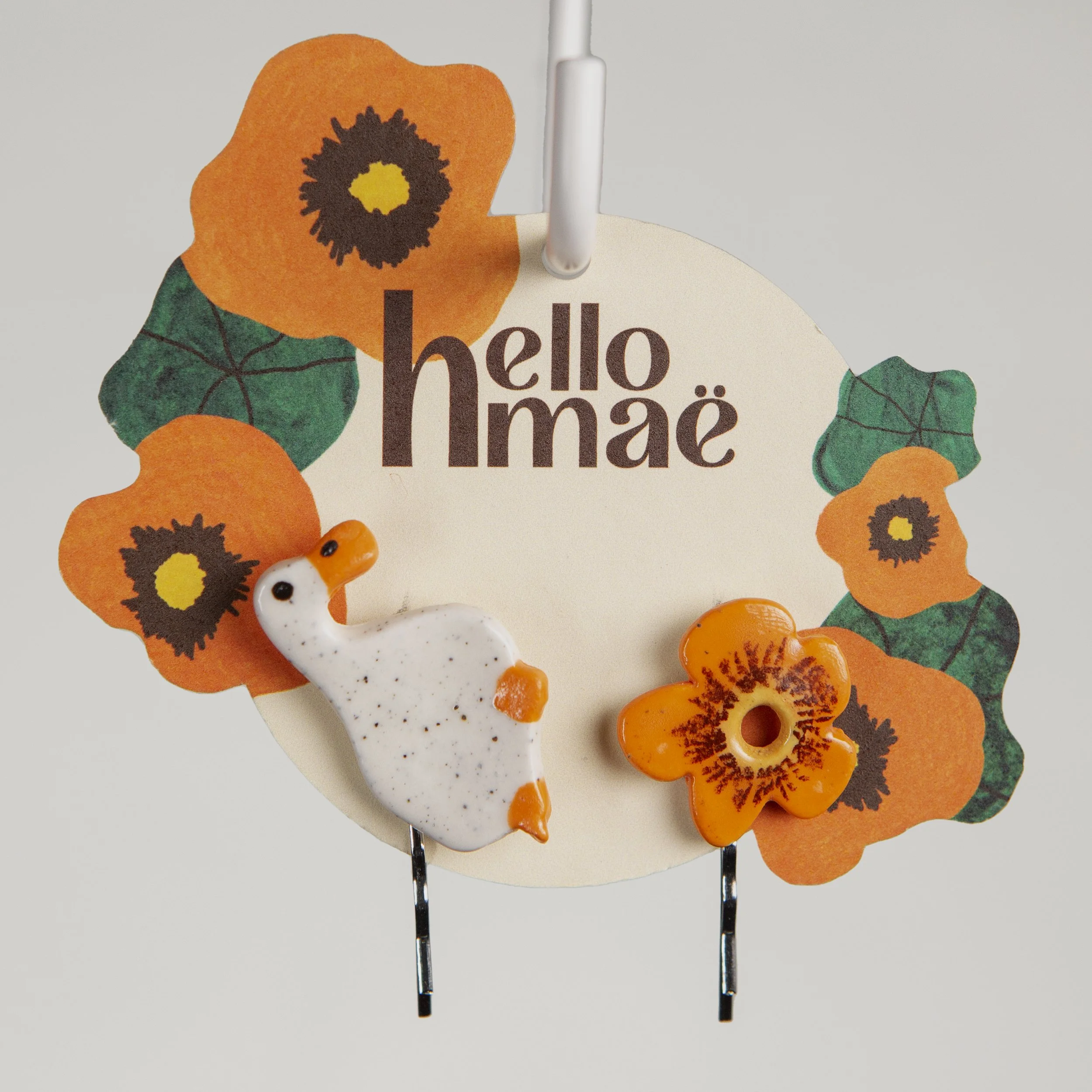 A set of two ceramic hair pins – one is a white flower and the other a dreamer white duck, handmade and painted.