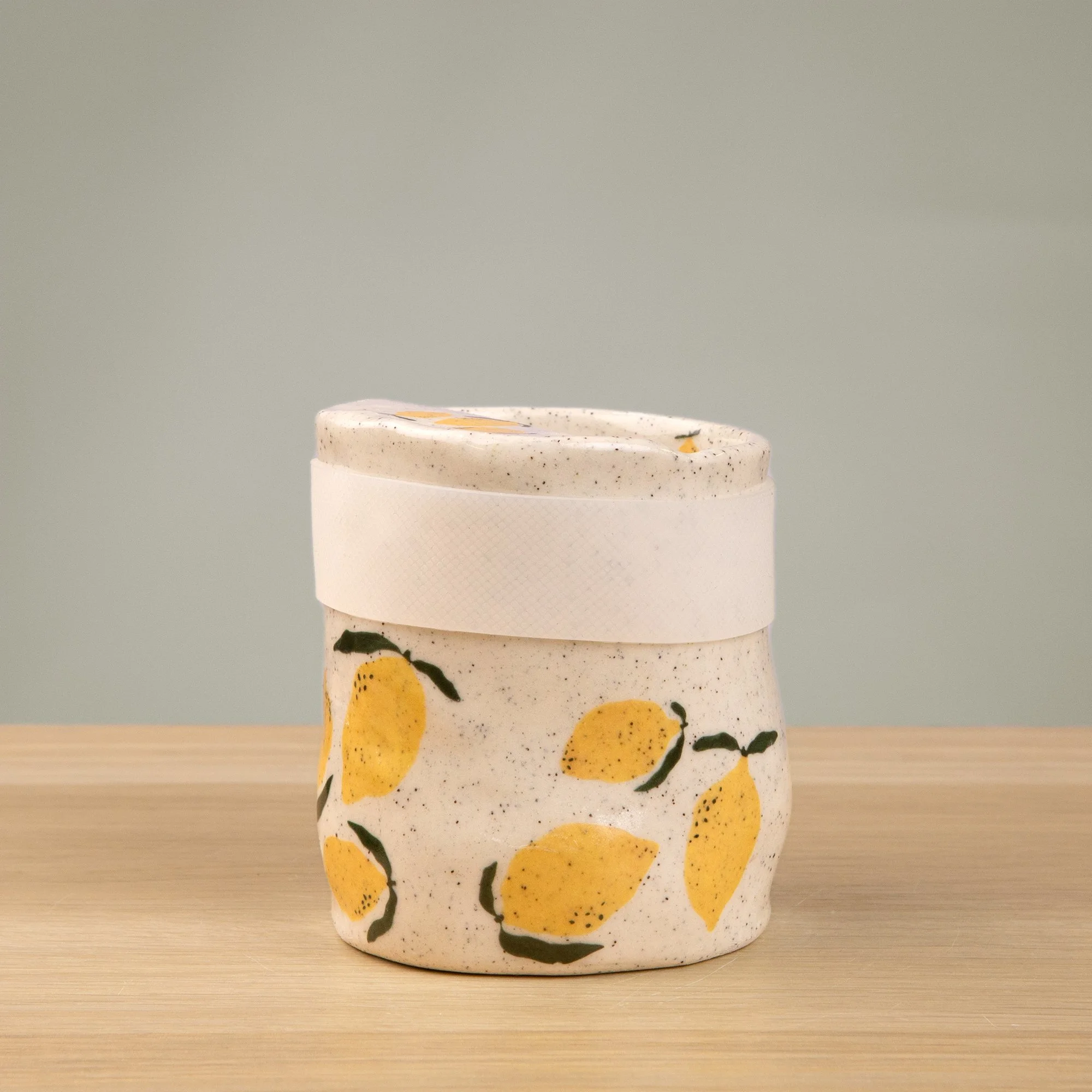 Handmade speckled ceramic lemon travel cup decorated with sweet lemon illustrations