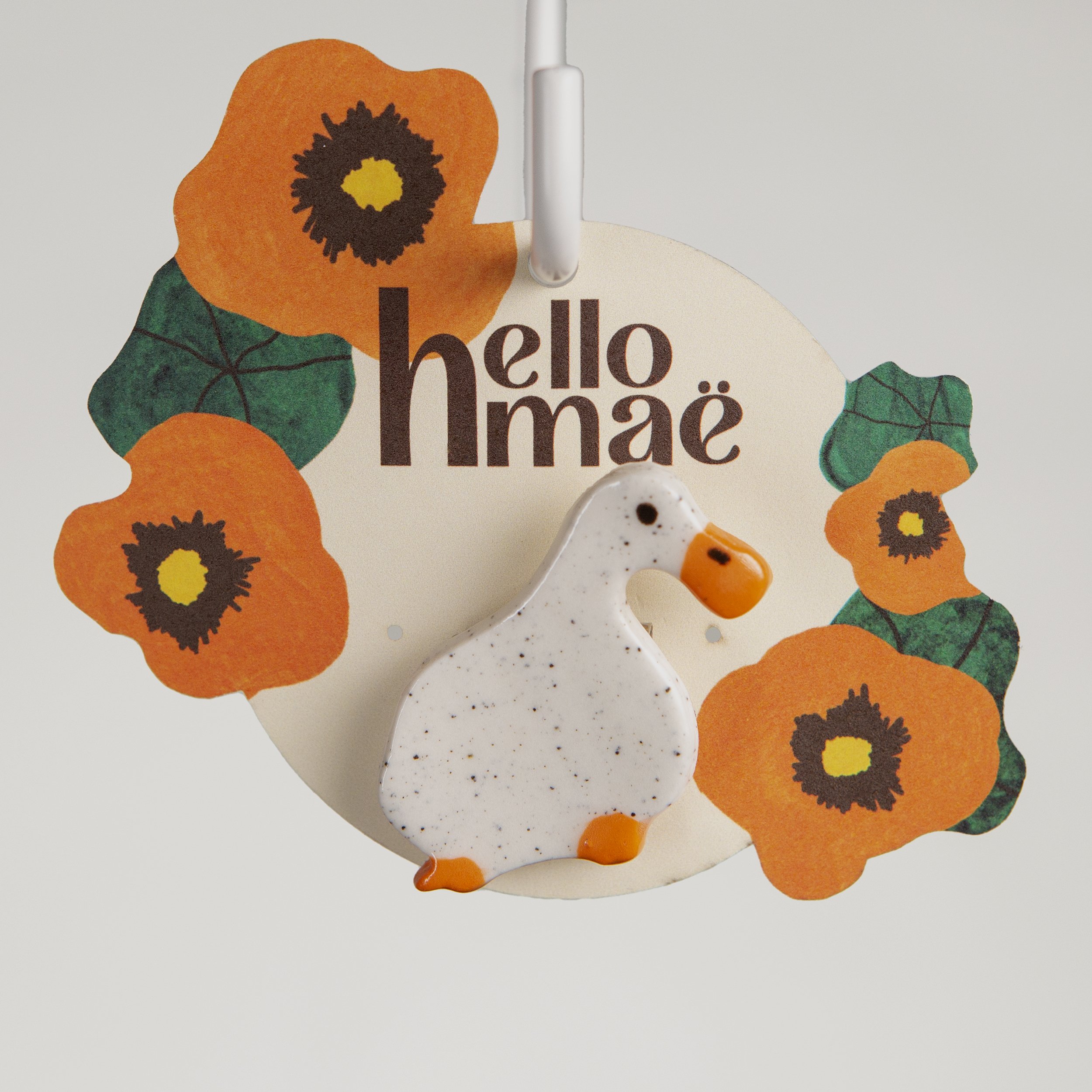 Handmade ceramic brooch with a glossy dreamer white duck, photographed on a neutral background