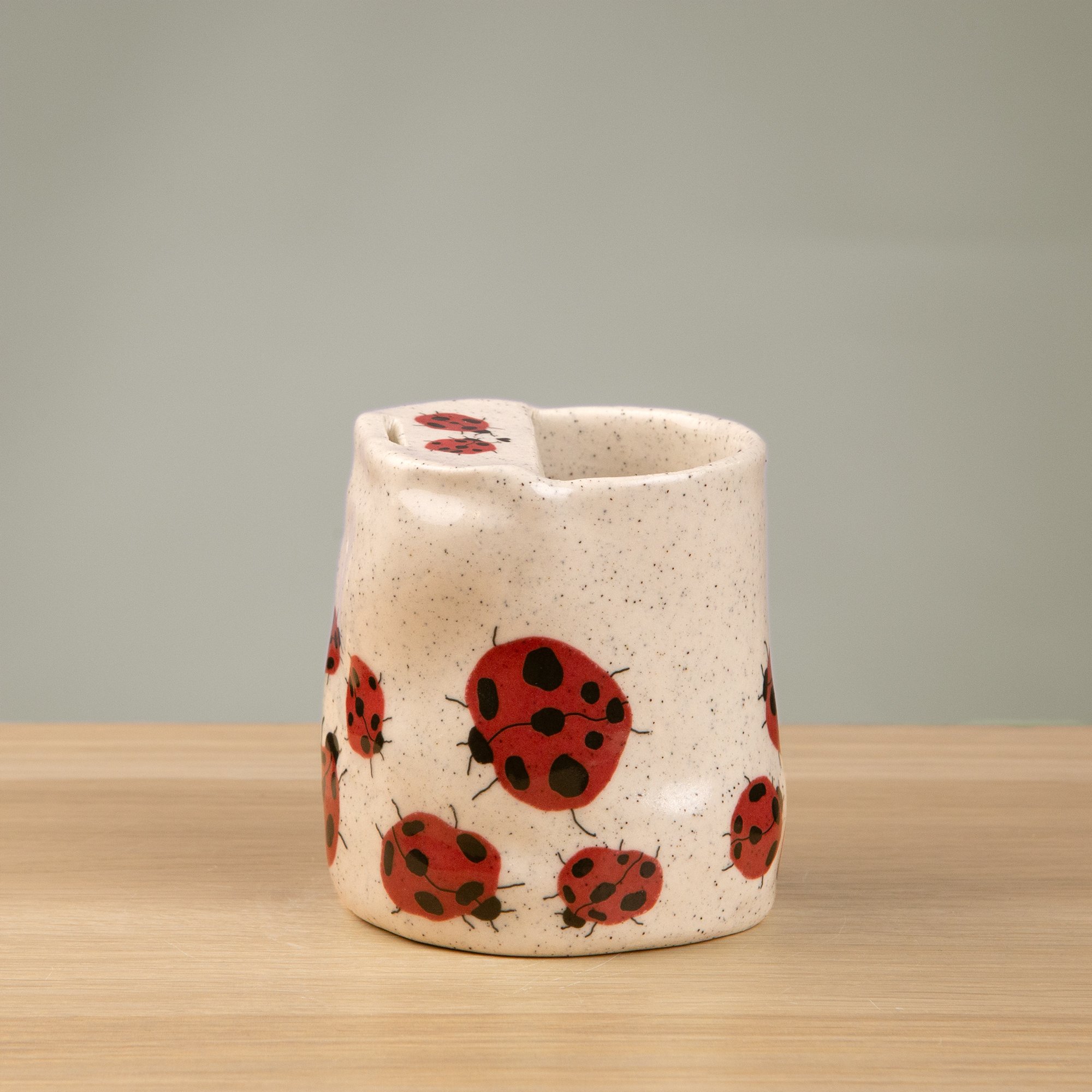 Handmade speckled ceramic Loveliness travel cup decorated with cheerful red ladybugs