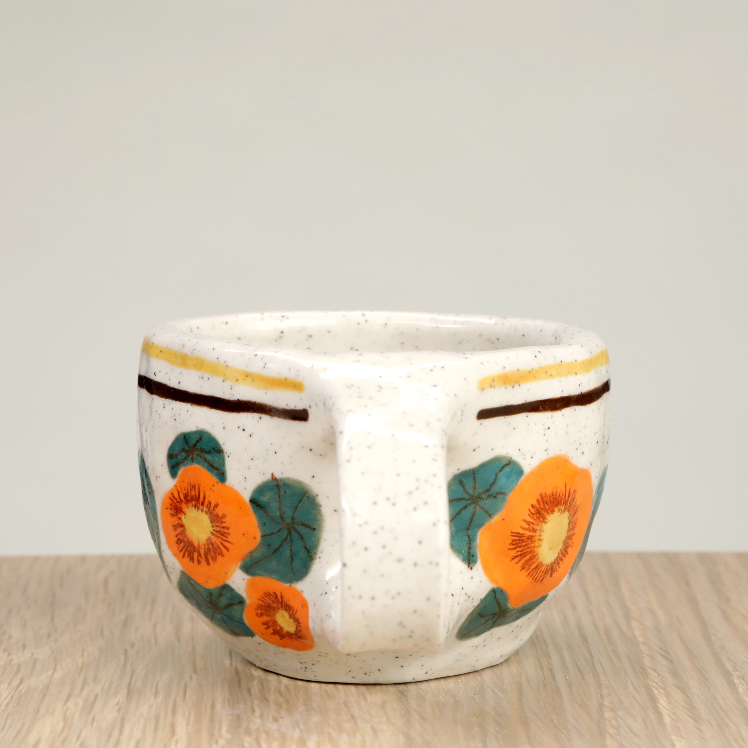 Handmade ceramic coffee cup with hand-painted nasturtium flowers & 2 lines border, crafted from speckled clay in Melbourne. Holds approximately 150ml.