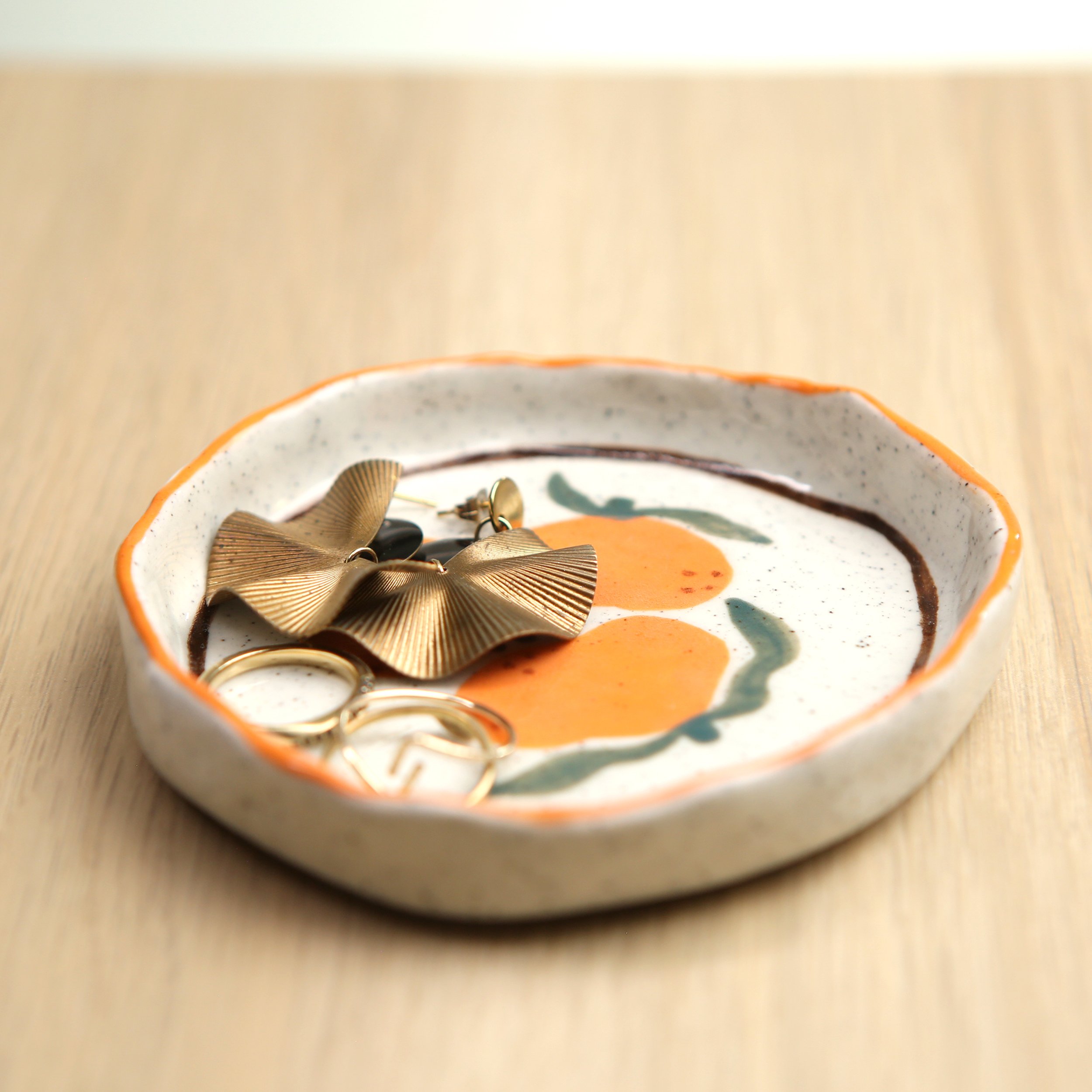 Ceramic trinket dish featuring mandarins and a orange/brown line border, 10cm diameter