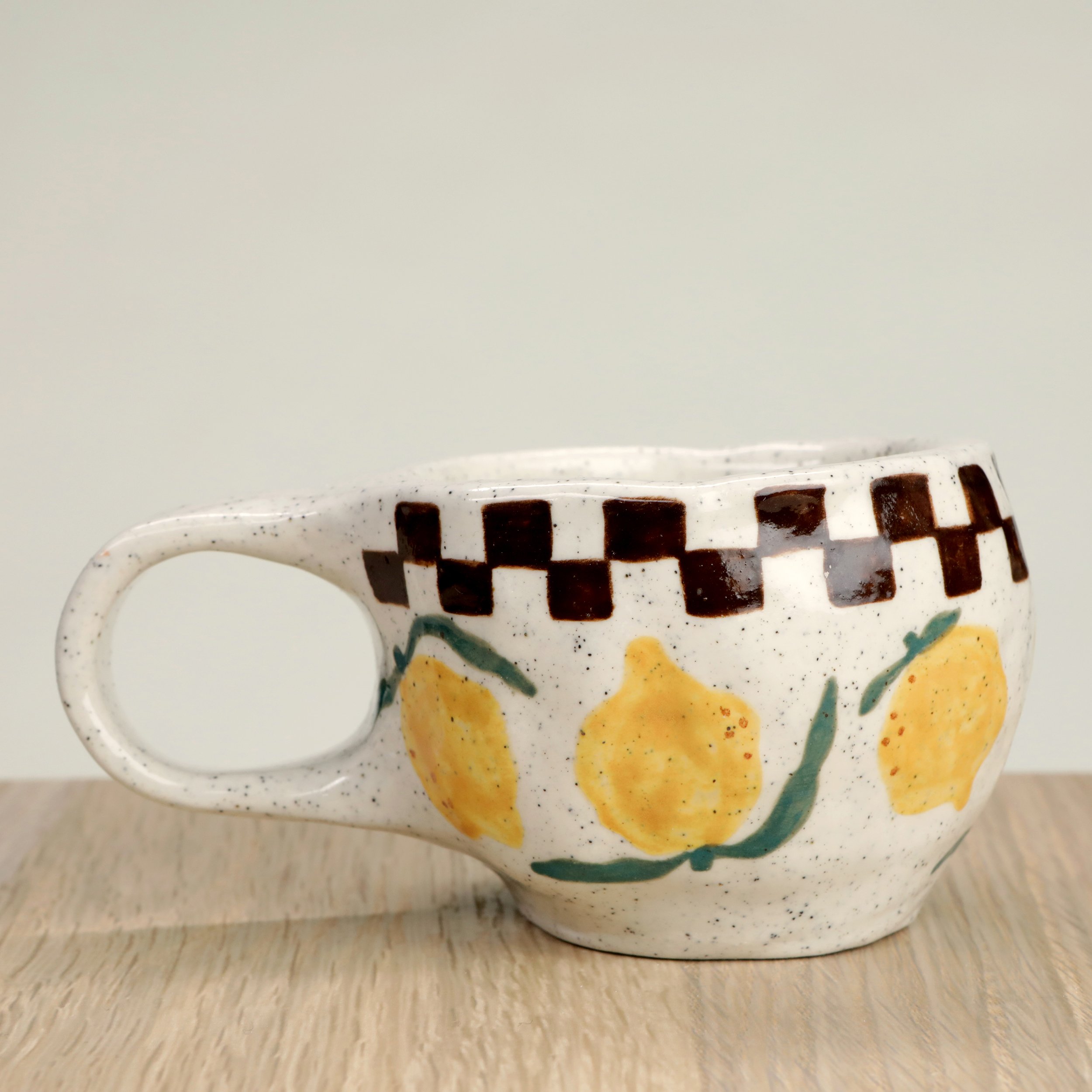 Handmade ceramic coffee cup with hand-painted lemons & a chocolate check border, crafted from speckled clay in Melbourne. Holds approximately 150ml.