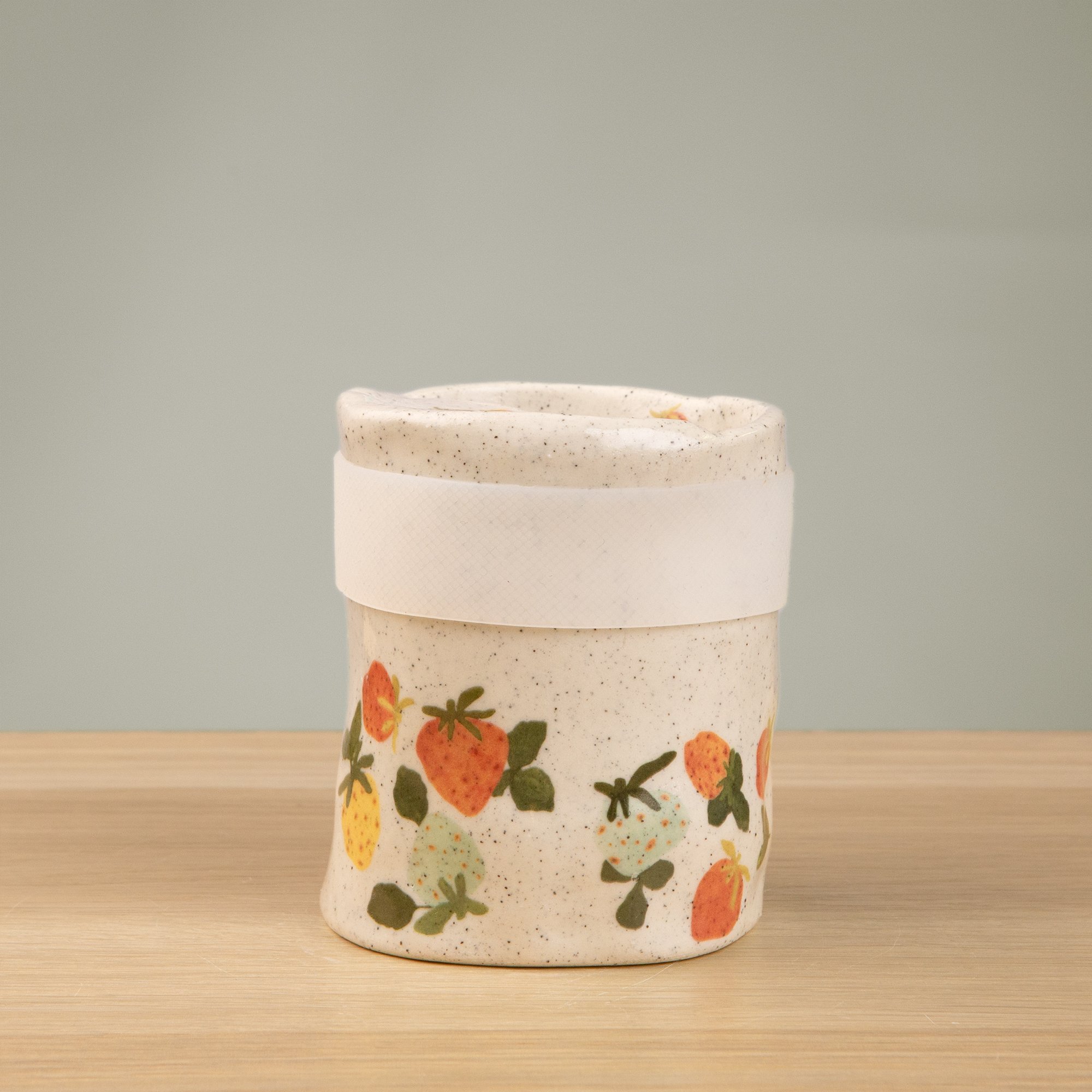 Handmade speckled ceramic strawberry dream travel cup decorated with sweet red, pink, yellow and blue strawberries