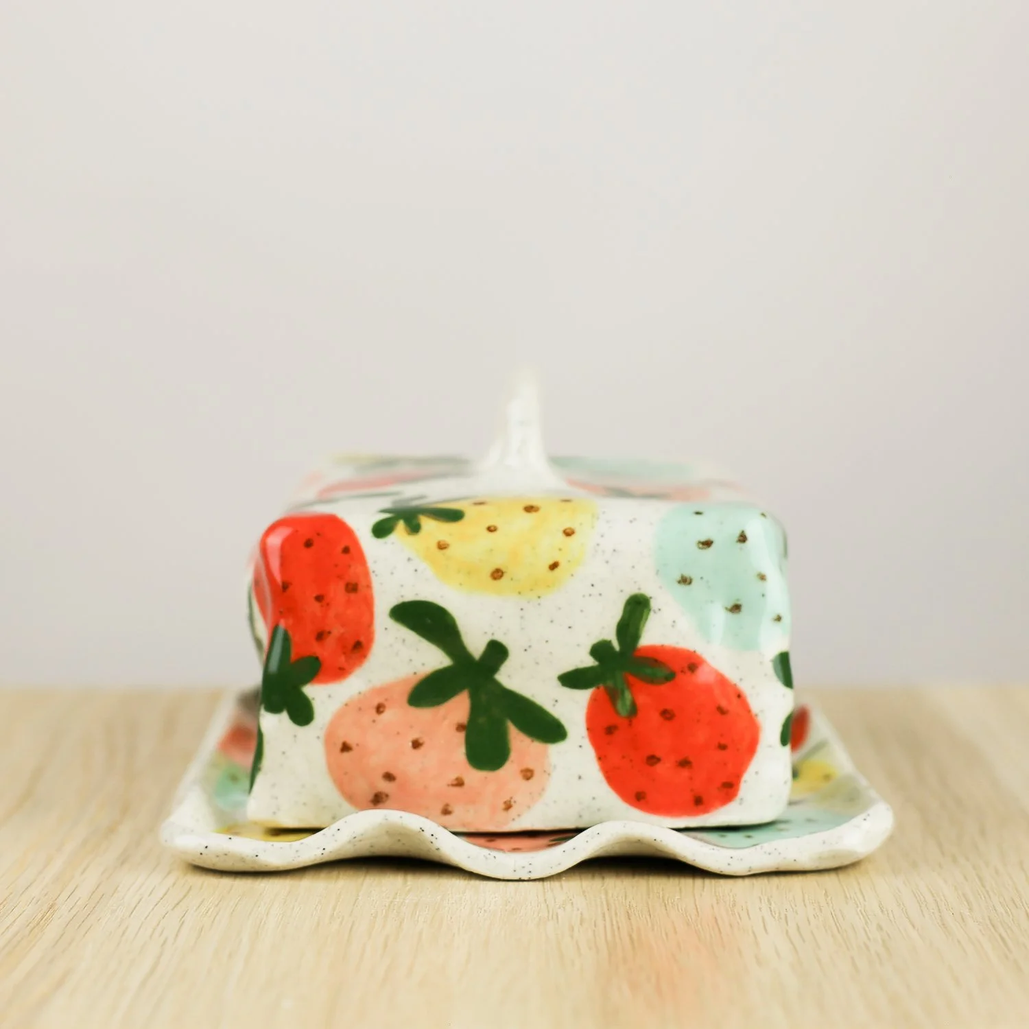 Handmade ceramic butter dish with hand-painted strawberries , set on a white background.