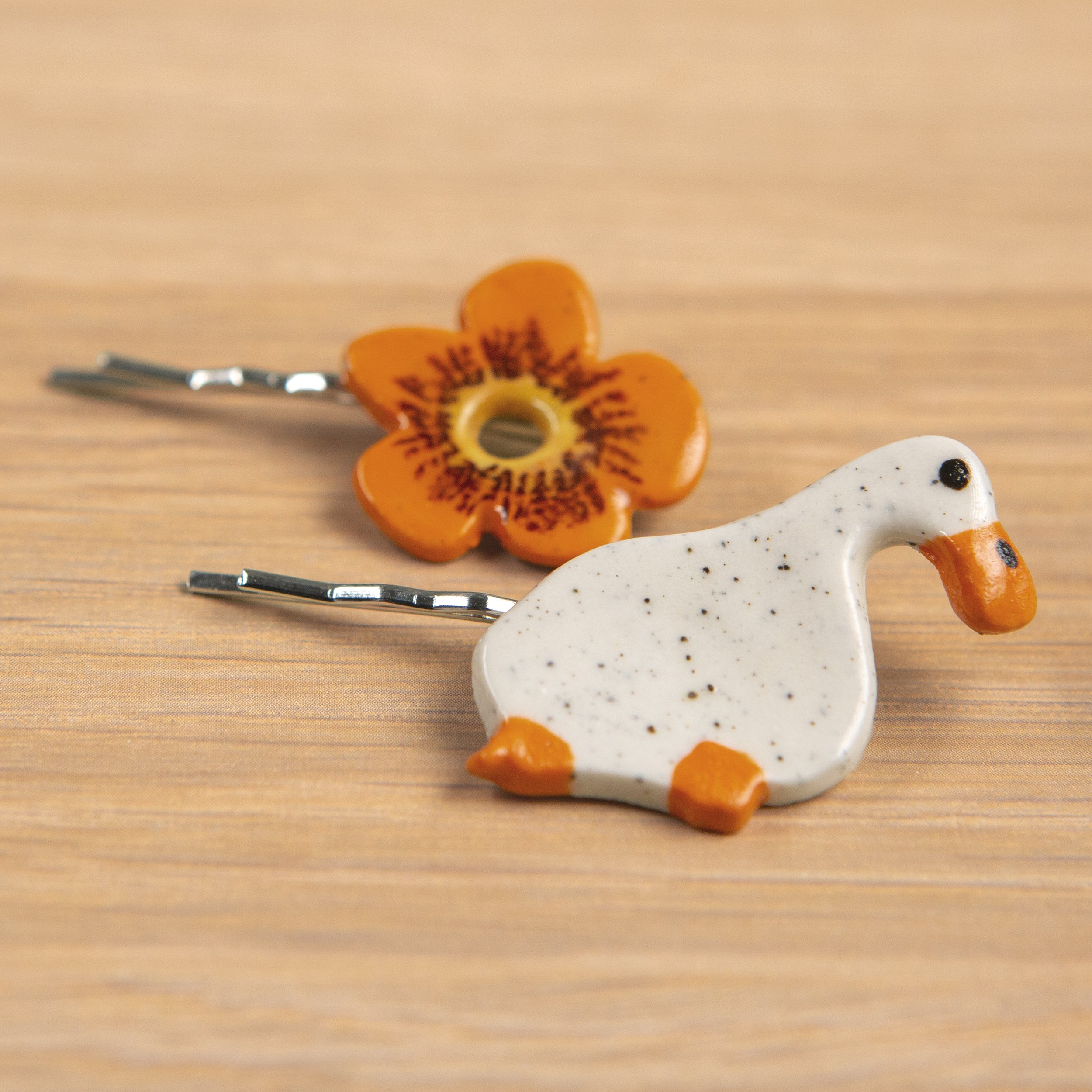 A set of two ceramic hair pins – one is a white flower and the other a dreamer white duck, handmade and painted.