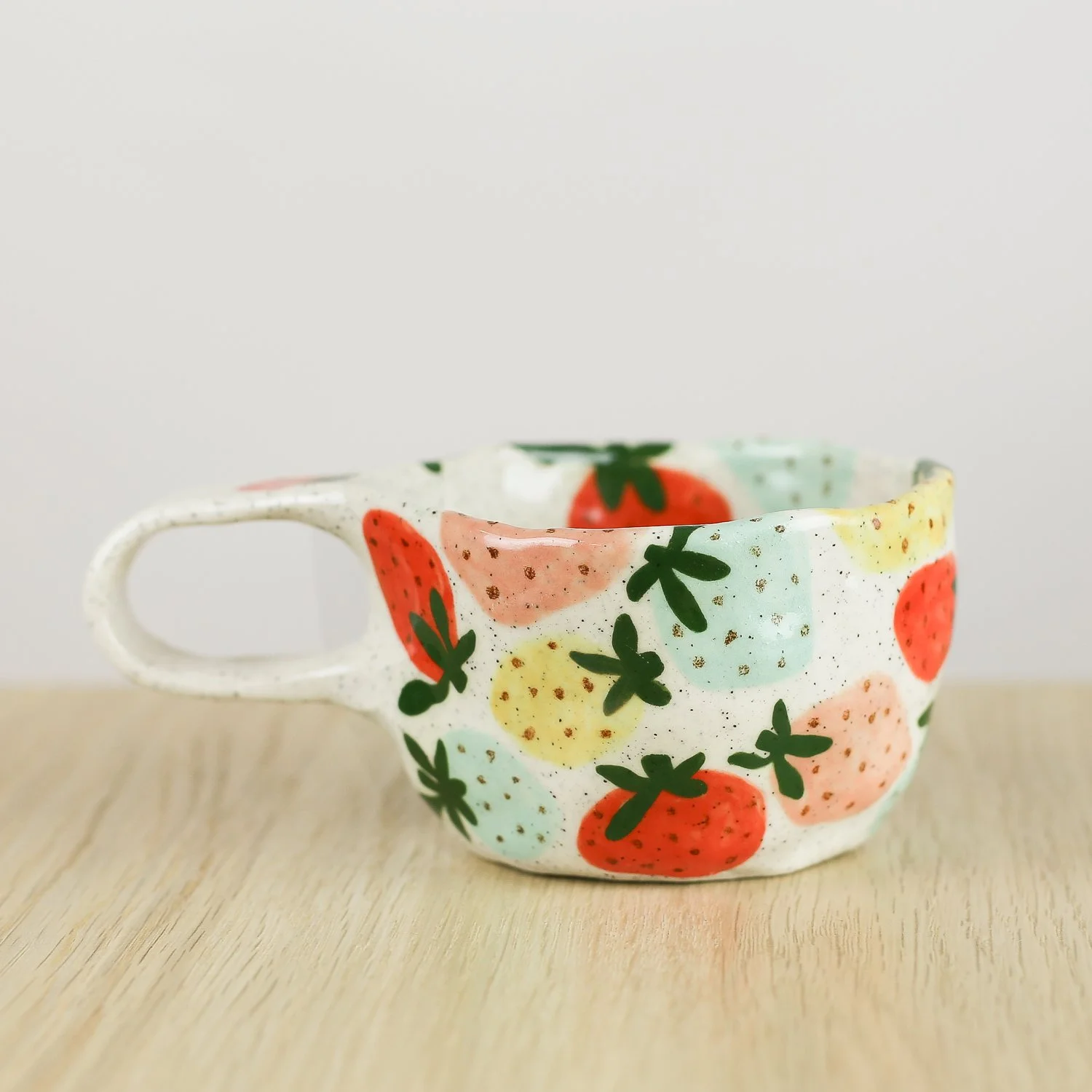 Handmade ceramic cup with hand-painted strawberries in red, pink, yellow and blue. Holds 150ml. A unique, playful coffee cup for everyday use.