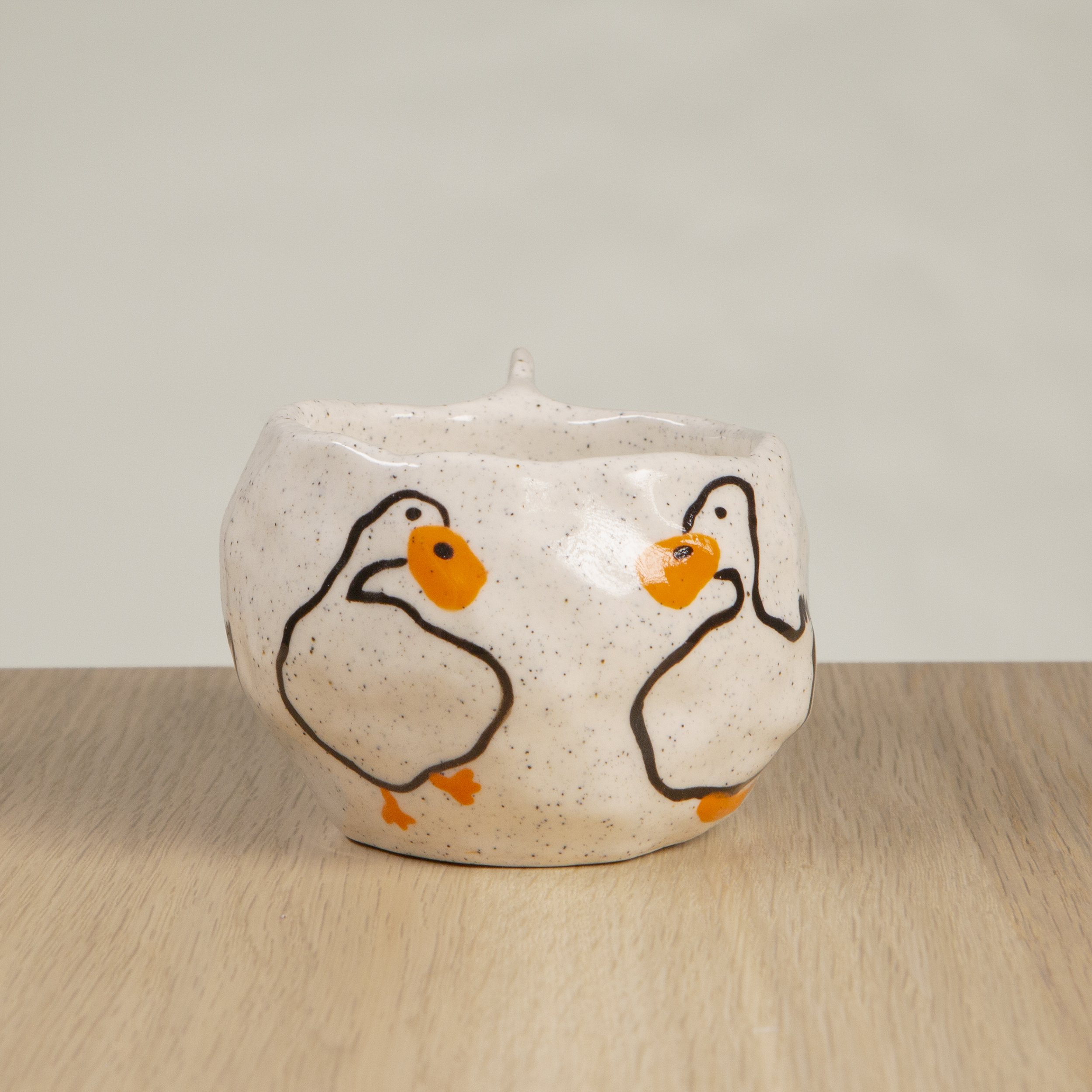 Handmade ceramic coffee cup with hand-painted loving ducks, crafted from speckled clay in Melbourne with a cute petal handle. Holds approximately 150ml.