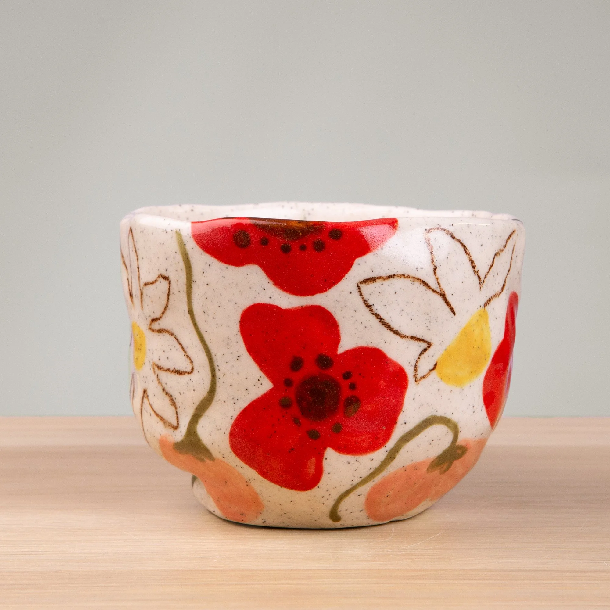 A soft garden in bloom, this handmade ceramic mug is adorned with hand-painted poppies, daisies and sweet pea flowers in a delicate, painterly style.