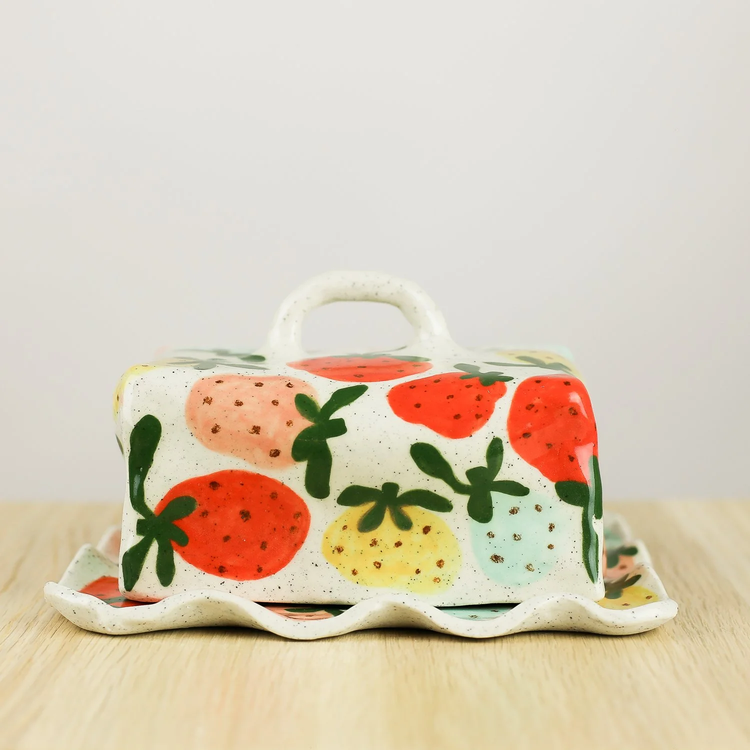 Handmade ceramic butter dish with hand-painted strawberries , set on a white background