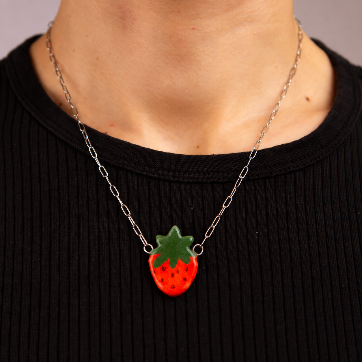 Handmade ceramic red strawberry necklace featuring a playful hand-painted strawberry pendant on a silver-coloured chain.