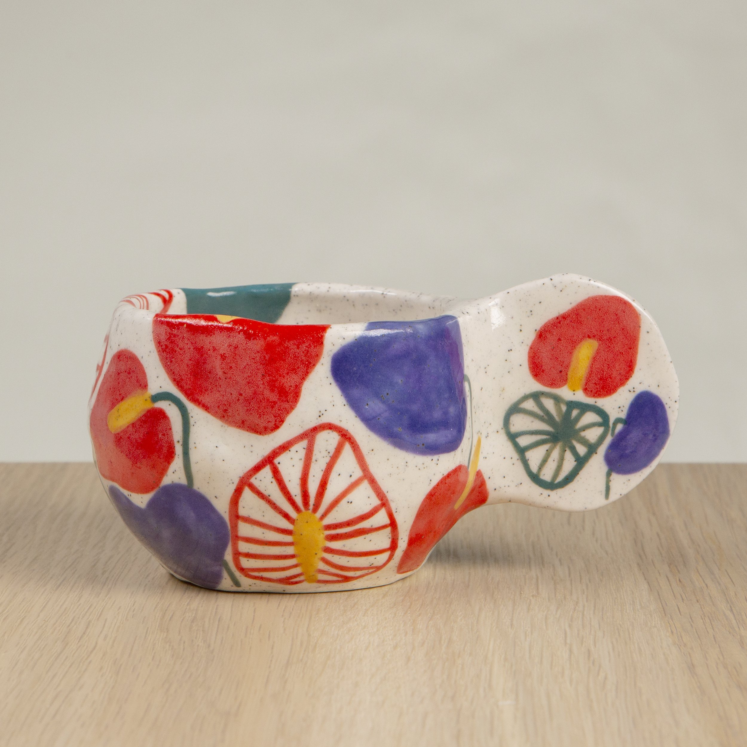 Handmade ceramic coffee cup with hand-painted anthurium flowers, crafted from speckled clay in Melbourne with a cute petal handle. Holds approximately 150ml.