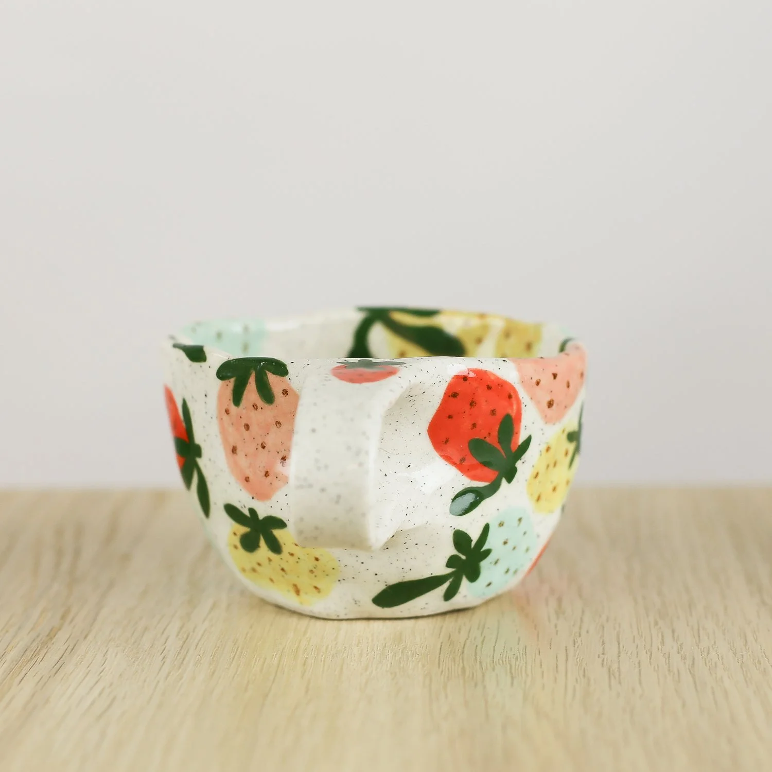 Handmade ceramic cup with hand-painted strawberries in red, pink, yellow and blue. Holds 150ml. A unique, playful coffee cup for everyday use.
