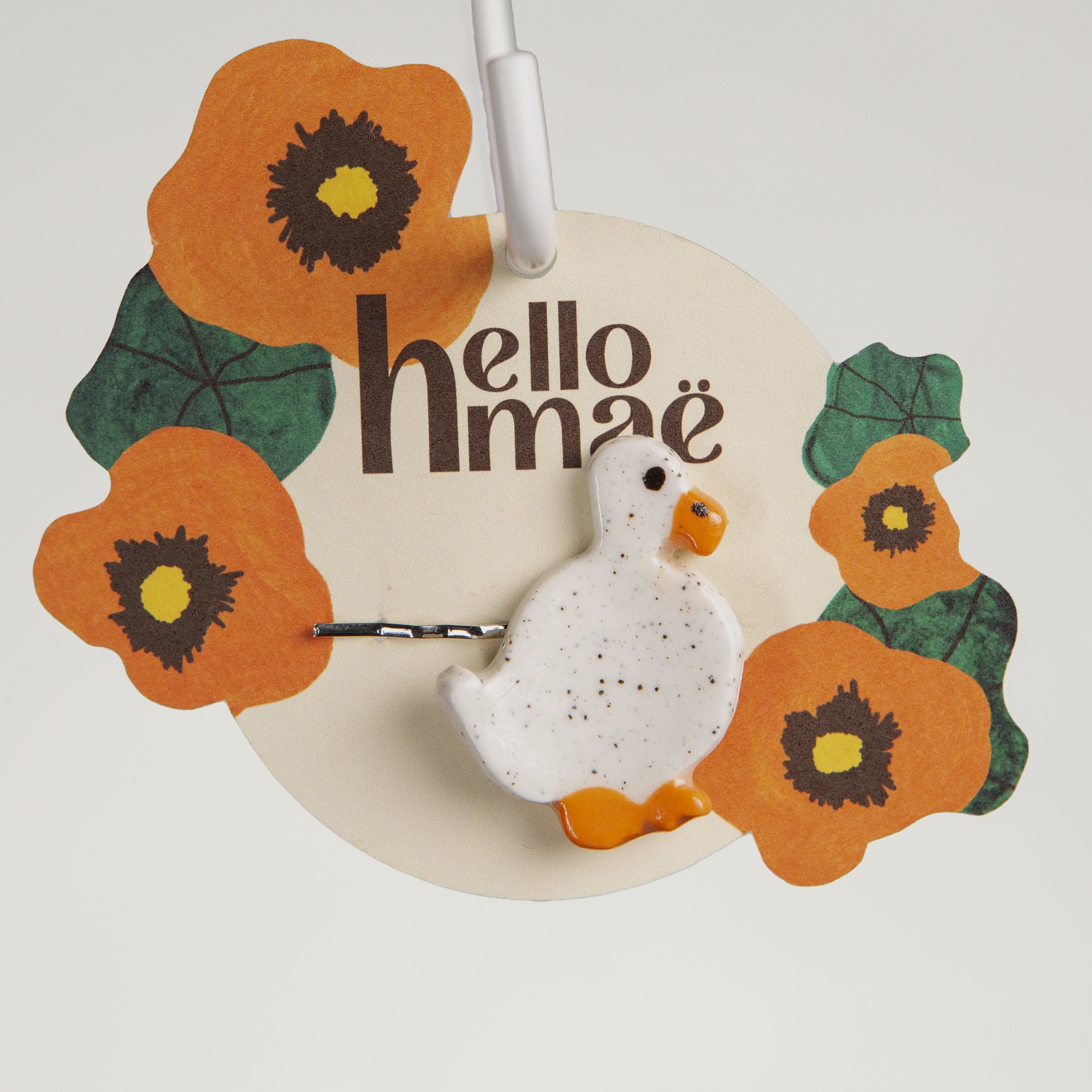 Handmade ceramic hair pin with a glossy wandering white duck, photographed on a neutral background.