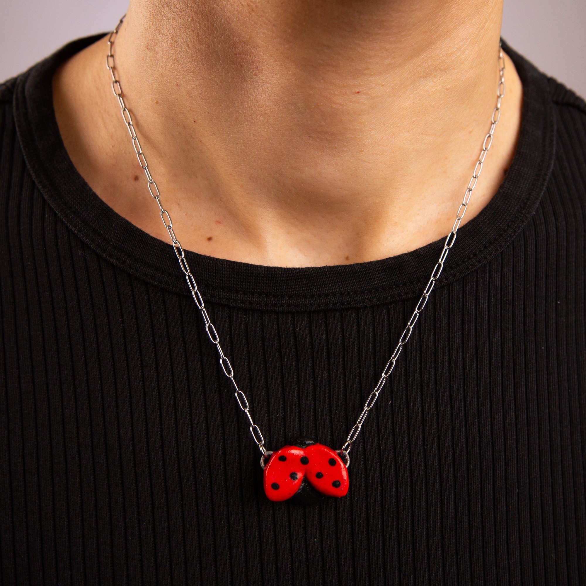 Handmade ceramic ladybug necklace featuring a playful hand-painted ladybug pendant on a silver-coloured chain.