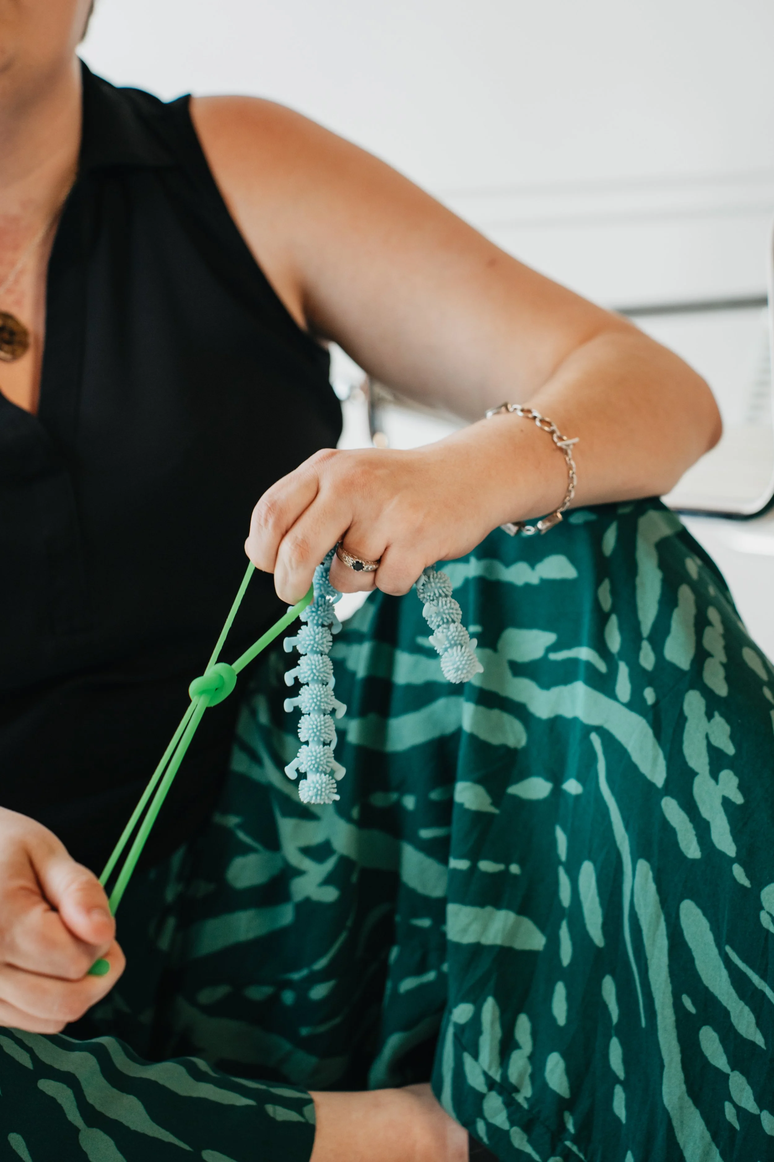 Hands demonstrating a green sensory fidget used for grounding, movement, and regulation.