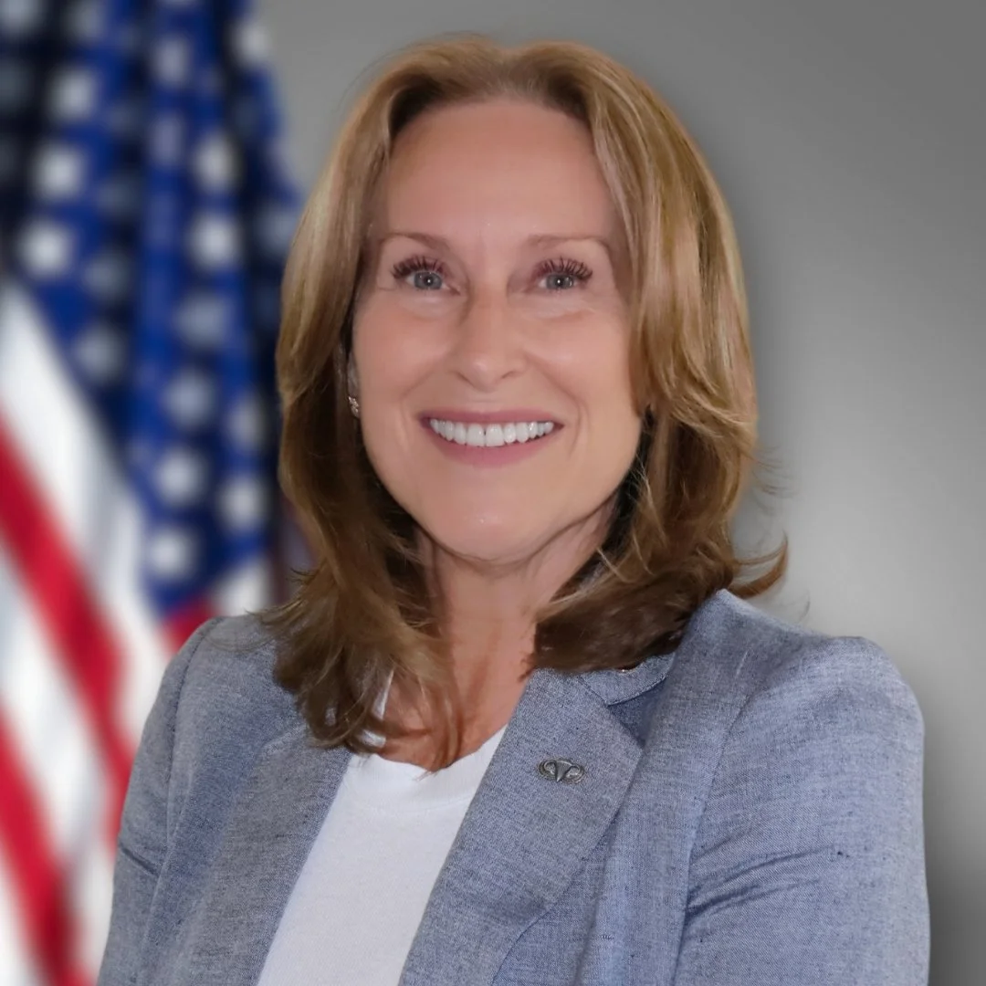 Congressional Candidate Maura Keller smililng at camera with American flag in background