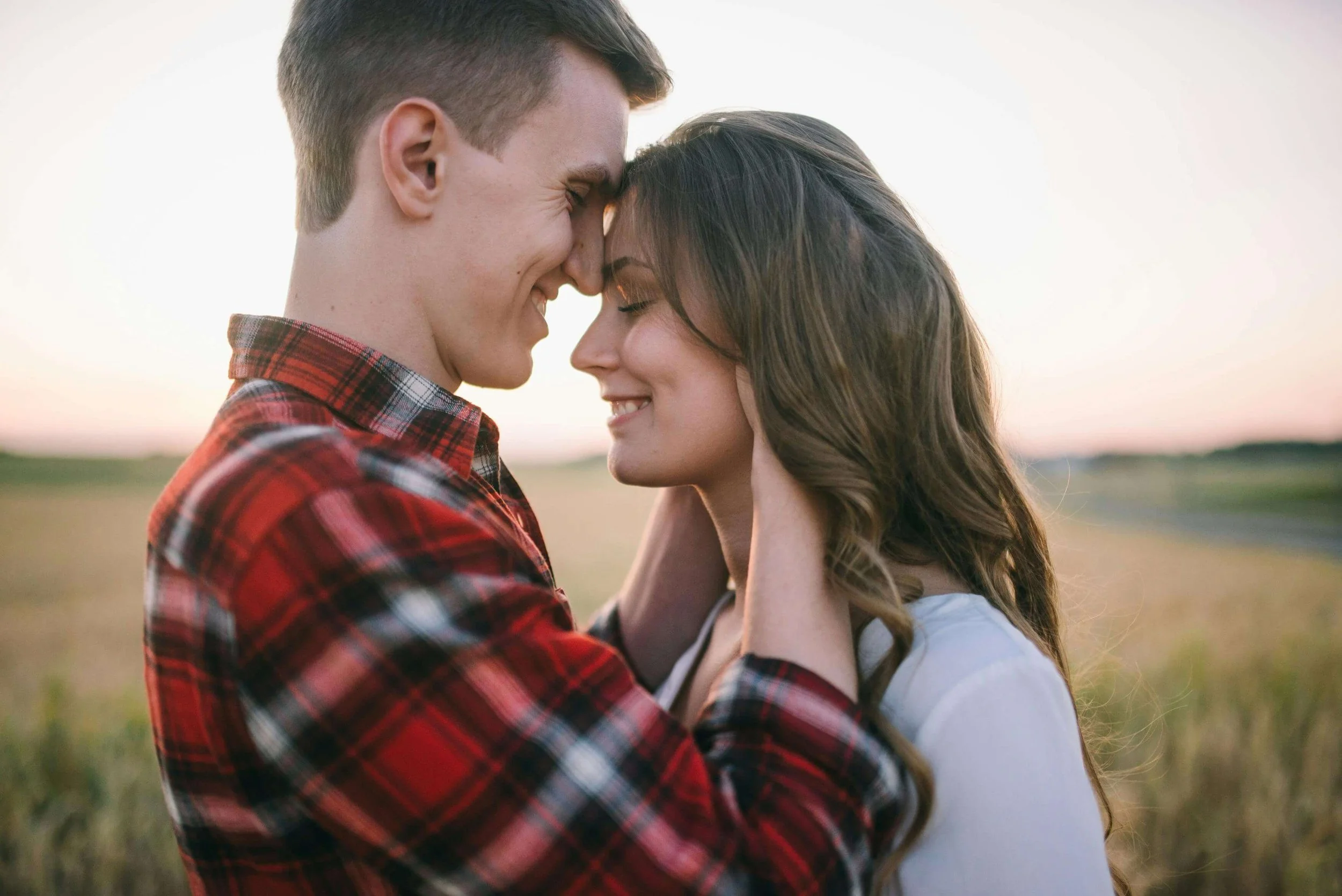 A couple smiles with foreheads touching. How can intimacy feel both deeper and more fragile after becoming parents? Working with a couples therapist in Arcadia, CA can support couples in nurturing their bond alongside parenthood.