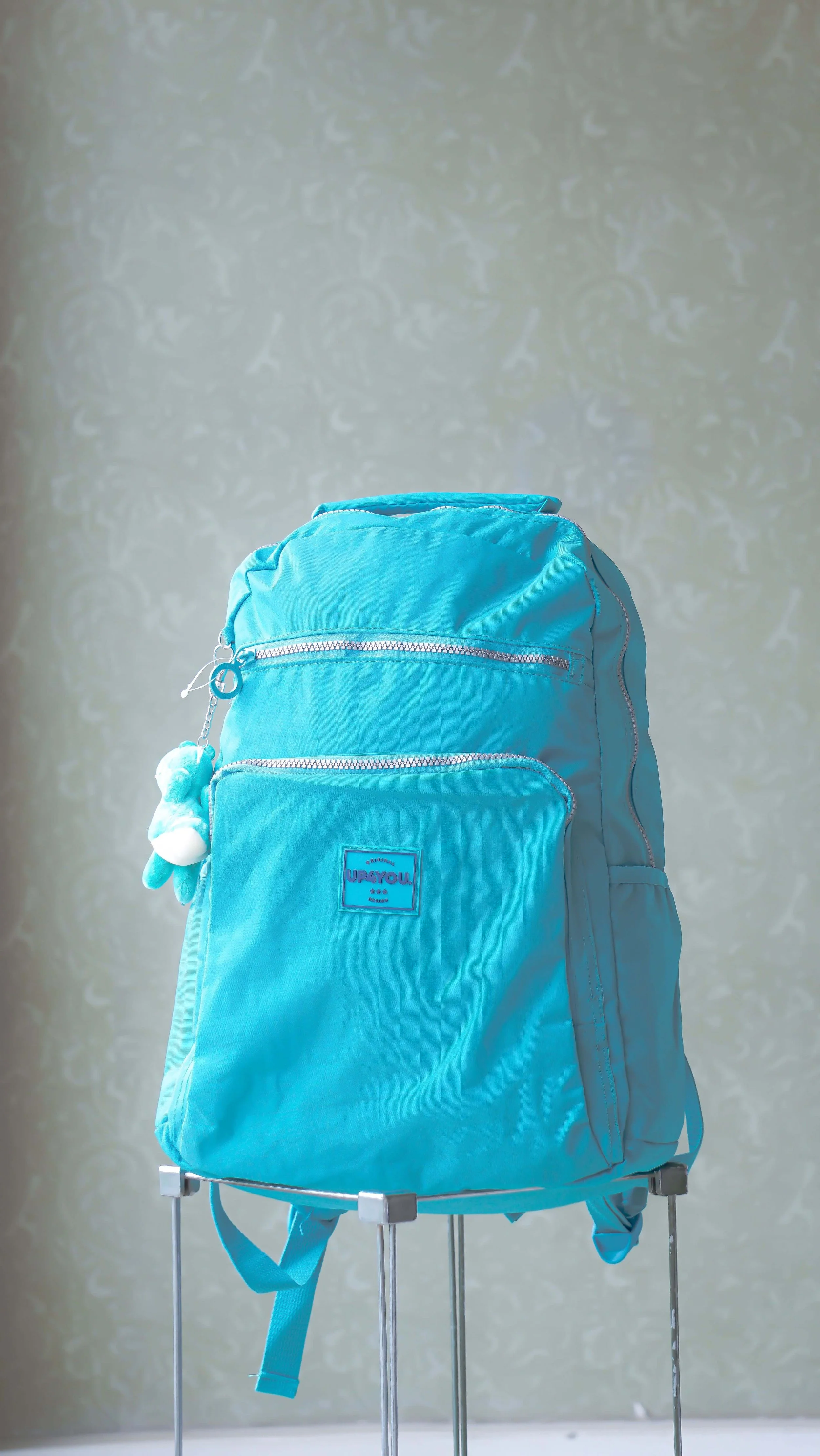A child's blue backpack sits on top of a grey side table.