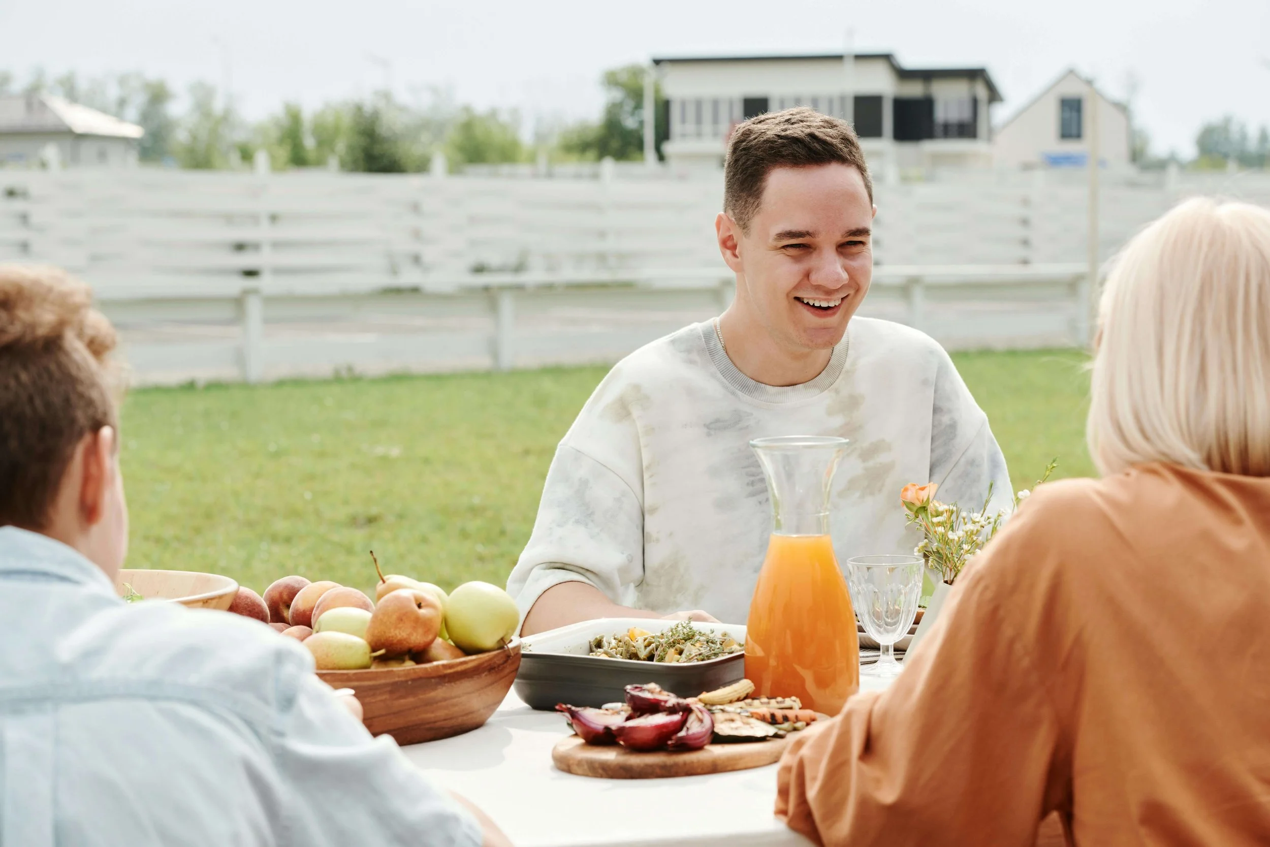 A teen boy smiles while sharing an outdoor meal with family. When parents manage academic pressure as a team, the whole family feels more connected and supported. Couples therapy in Arcadia, CA, can help you find that balance together.