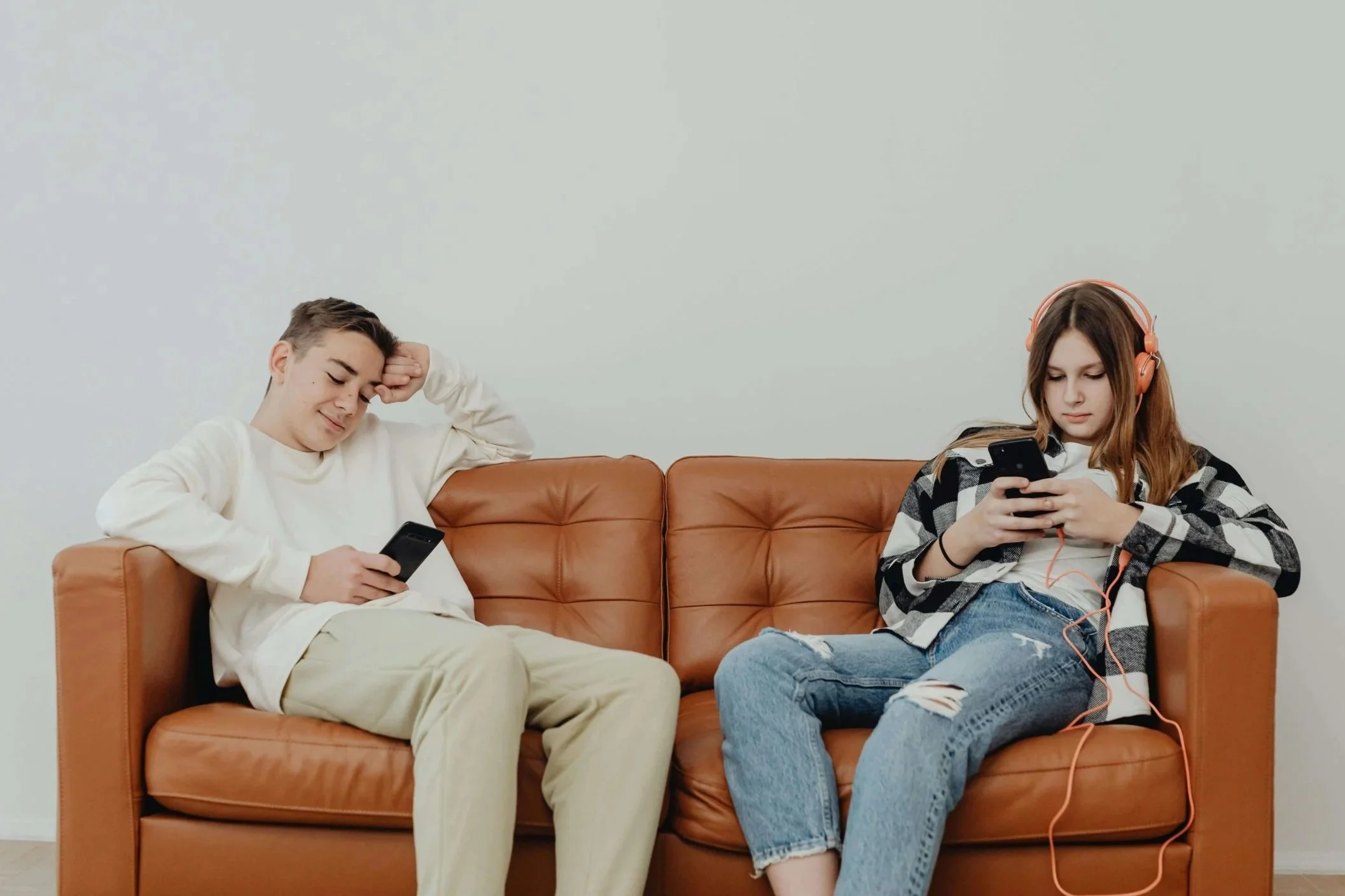Two teens sit separately on a leather couch, each absorbed in their own phones. What happens when screen time replaces face-to-face family connection? A couples therapist in Arcadia, CA, guides parents toward healthier tech boundaries together.