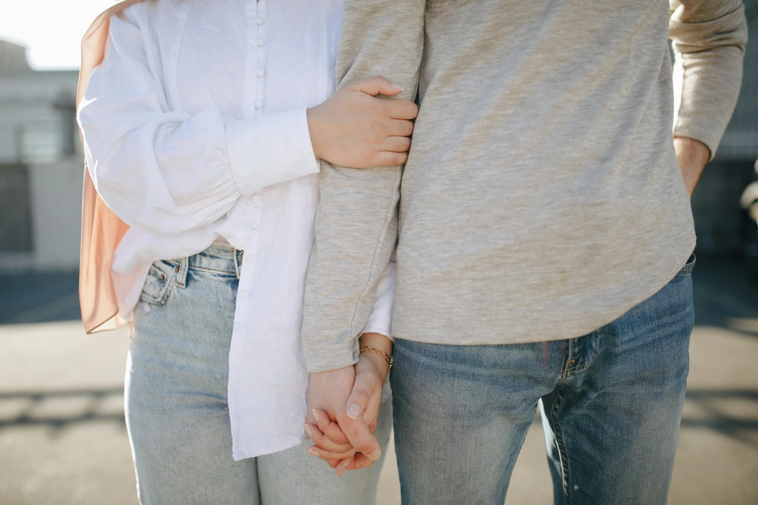 A couple holds hands outdoors. Can parent partnership help you present a united front when addressing teen peer pressure? A couples therapist in Arcadia, CA, strengthens your approach to raising teens collaboratively.