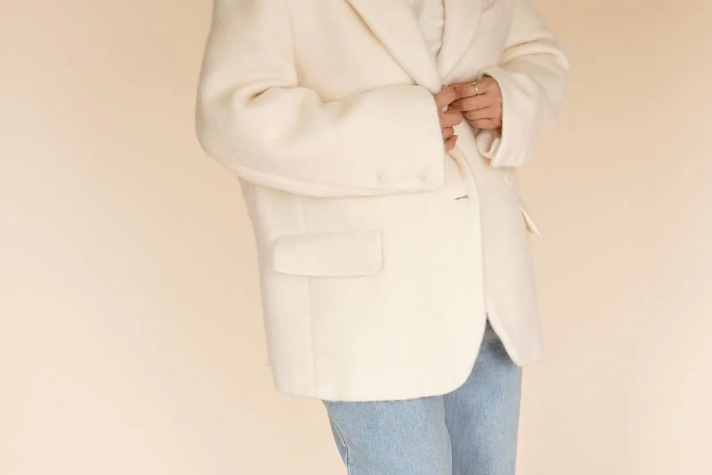 Close-up of Ivory wool-blend coat showing double button closure and soft-textured wool-polyester fabric for a cozy finish