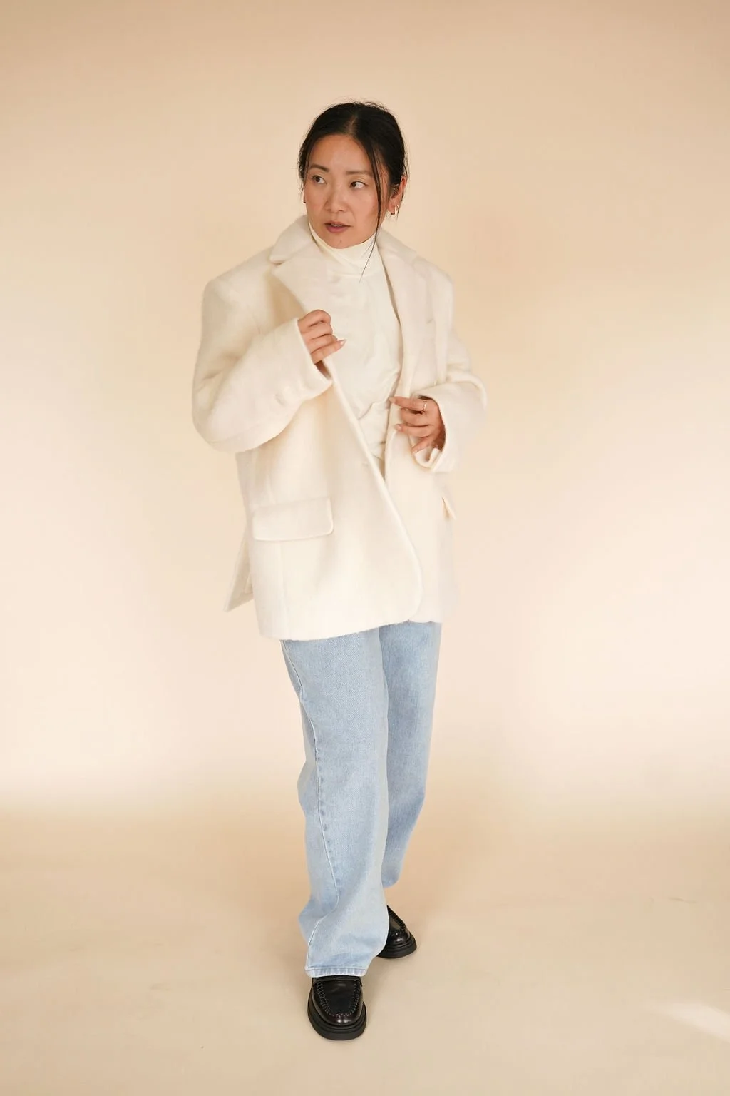 Ivory wool-blend coat styled as a layering piece, paired with jeans and black loafers for an elevated outfit