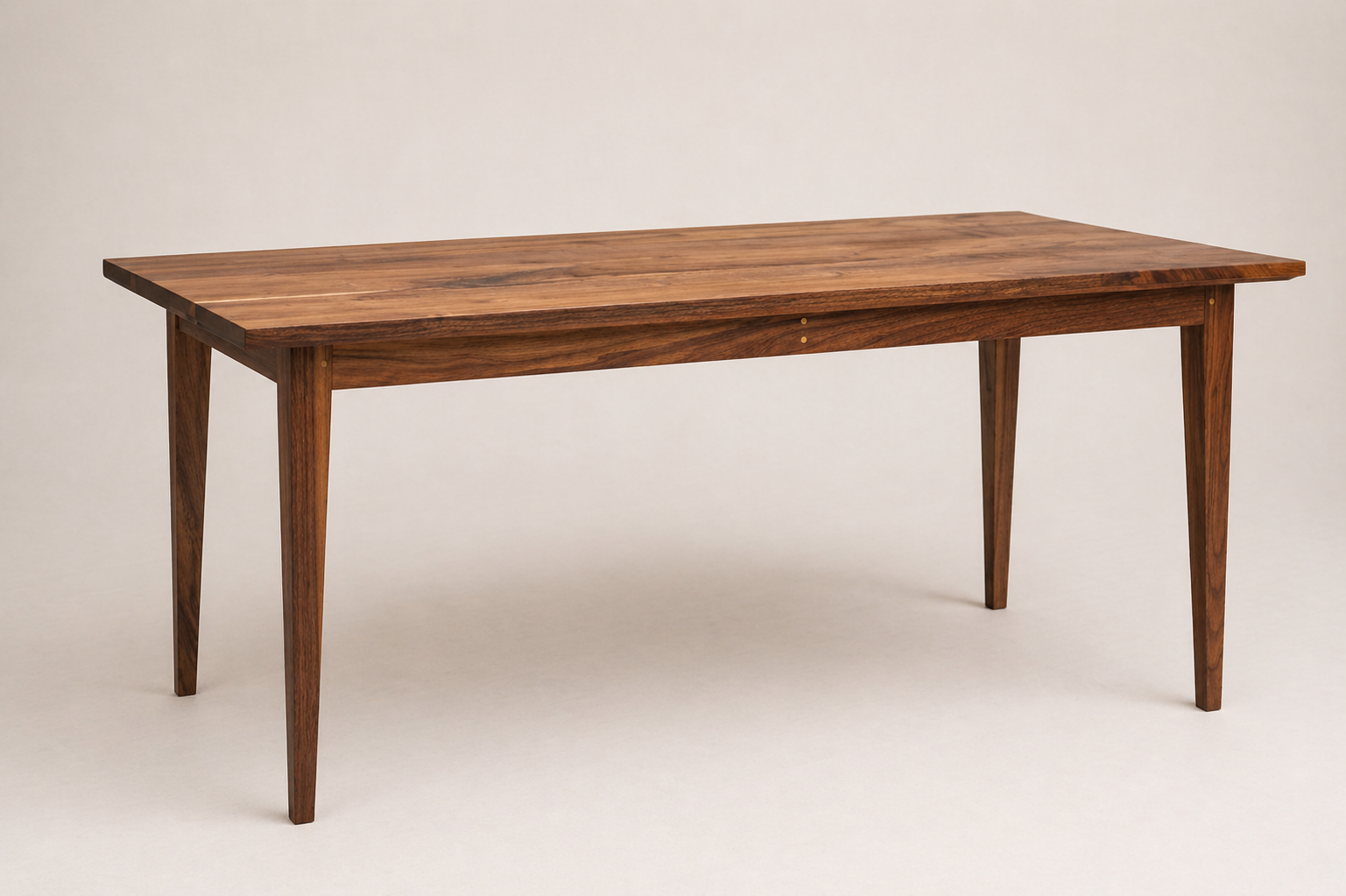 A wooden dining or office table with four tapered legs against a plain light background.