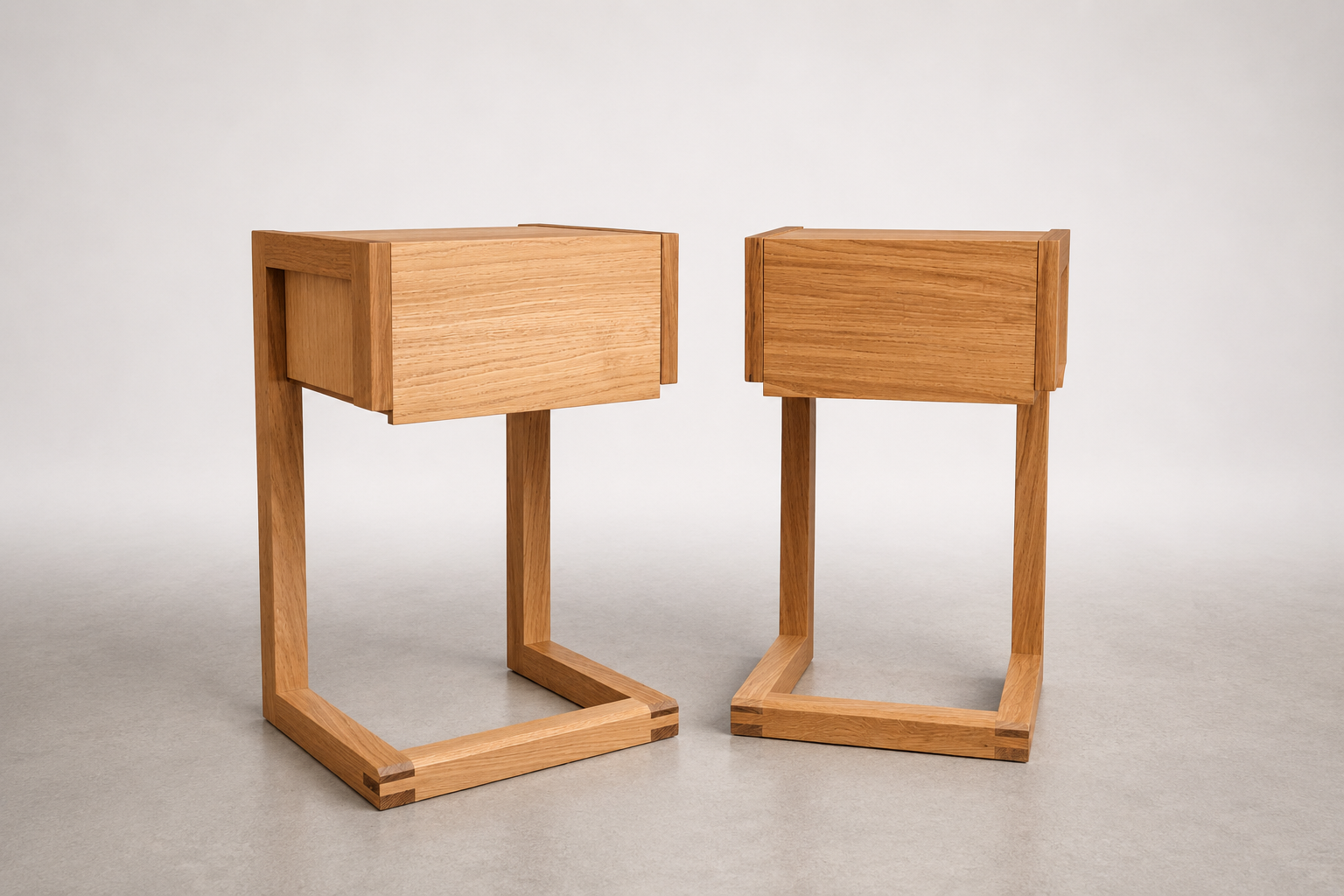 Two modern wooden tables with rectangular drawers and geometric bases, set against a neutral background.