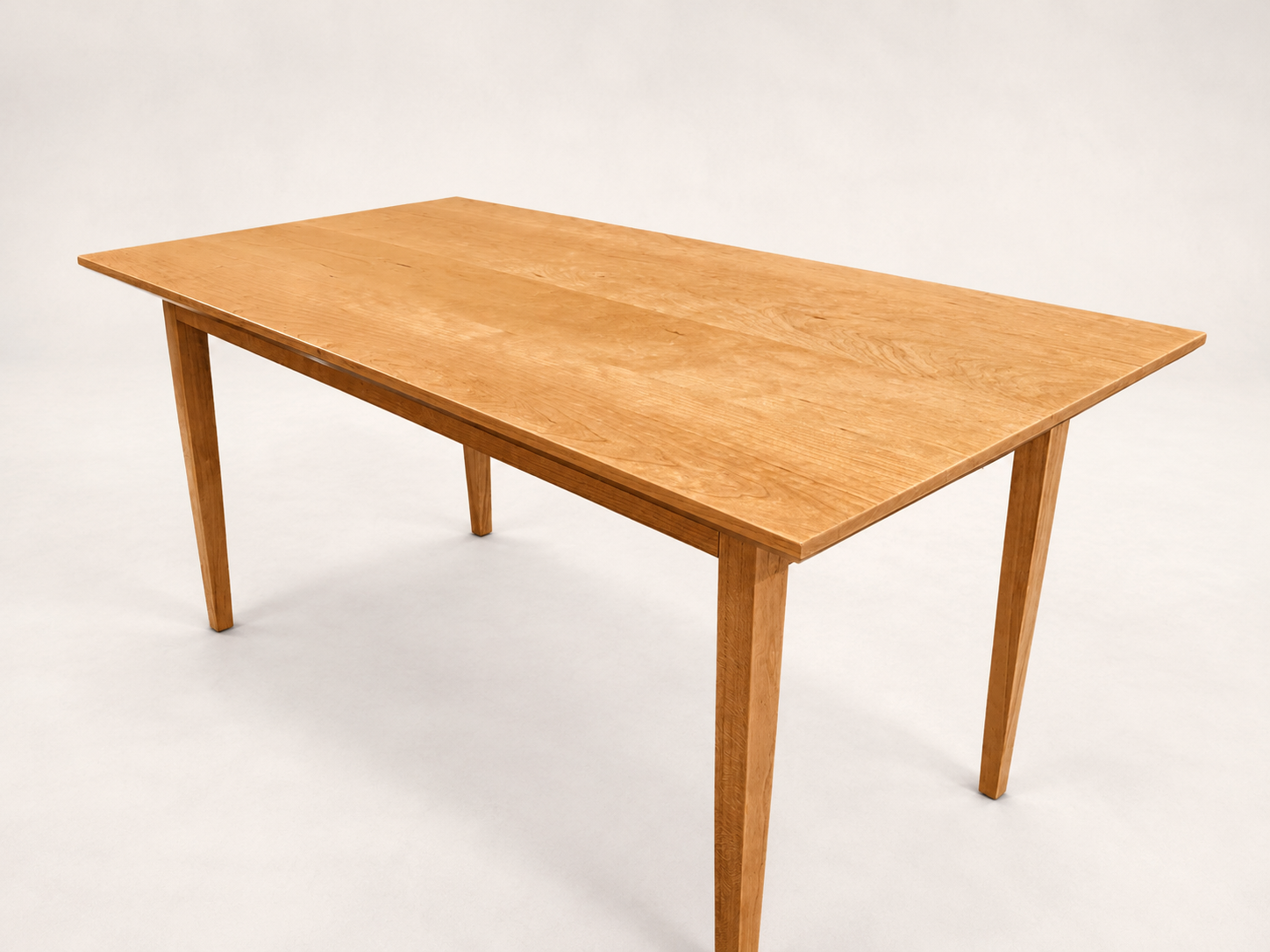 A wooden dining table with four legs on a plain light background.