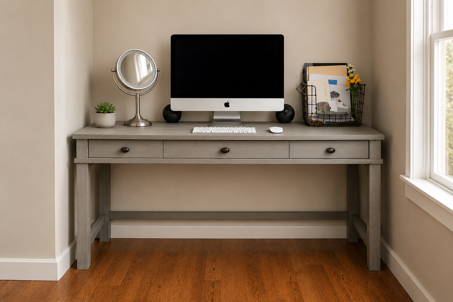 A home office desk setup with a computer, mirror, potted plant, and storage basket with papers and flowers.