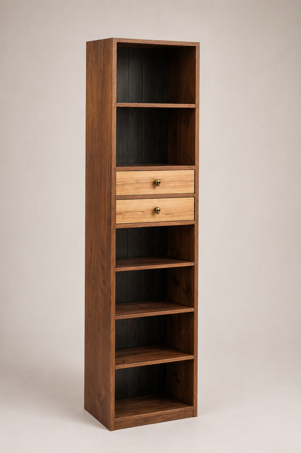 A tall wooden bookshelf with three open shelves, two drawers with skull-shaped knobs, and dark interior back panels, standing against a plain wall.
