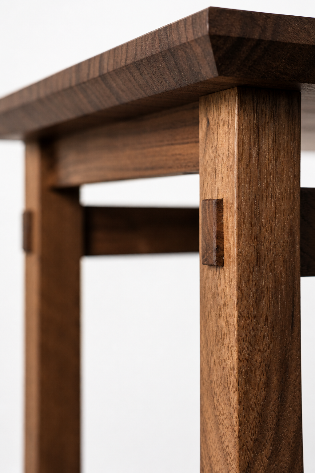 Close-up view of a wooden table or chair leg with a smooth finish and visible grain, showing precise joinery and craftsmanship.