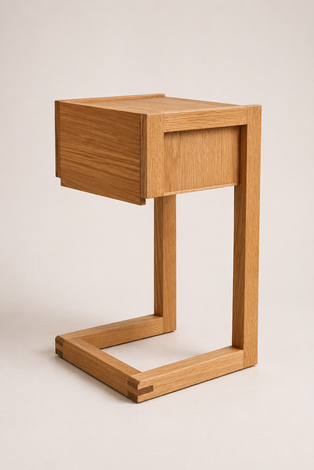 A minimalist wooden side table with a rectangular top and an attached drawer, supported by a geometric base.