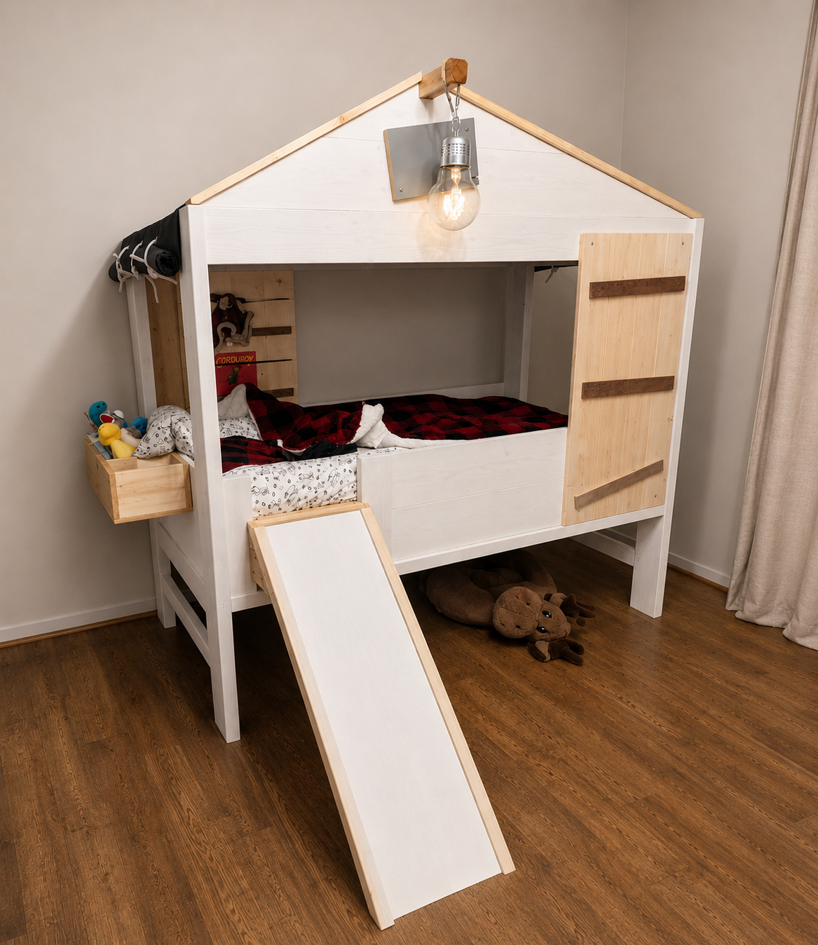 Children's indoor playhouse bed with a slide, stuffed animals underneath, and toys on a side shelf.