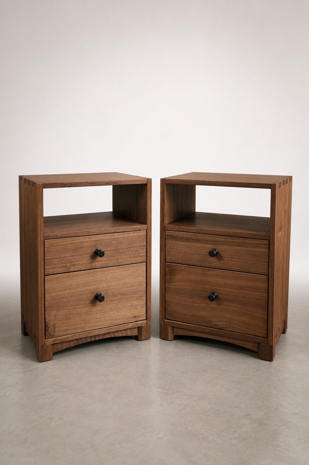 Two wooden nightstands with two drawers each, positioned on a light-colored floor against a plain white wall.