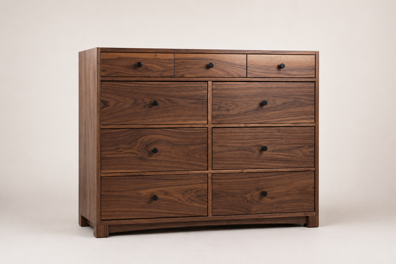 A custom black walnut dresser with nine drawers and black knobs, placed against a plain light-colored wall. Made by Von Boyle Woodworking Co.