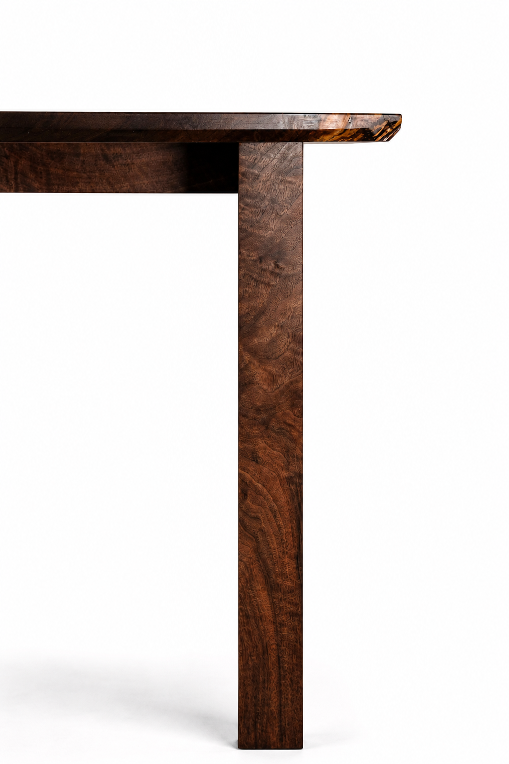 Close-up of a corner of a dark brown wooden table against a white background.