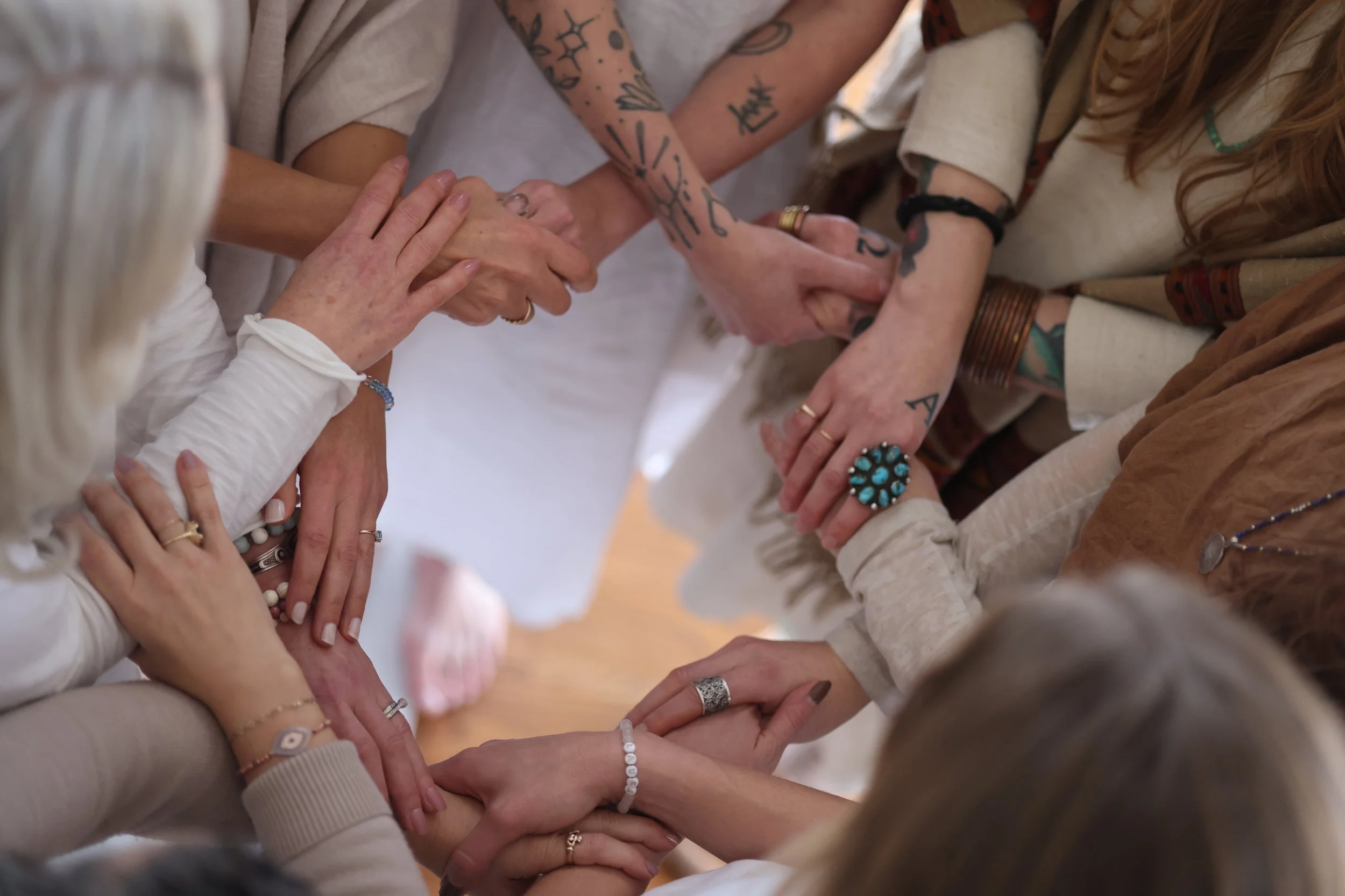 A group of diverse women holding hands in a circle, celebrating together.