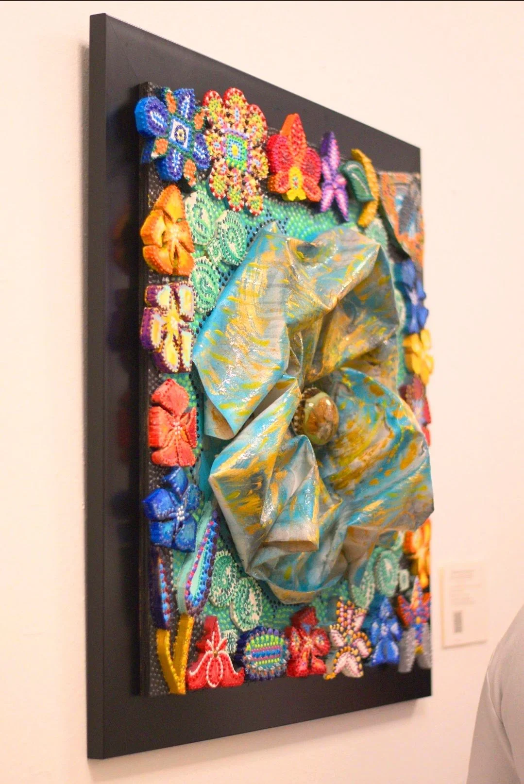 “Mixed media cosmic composition with textured central form surrounded by colorful floral shapes symbolizing the Earth element, by Laura Garcia.” Colors: Blue, red, yellow, green, purple, gold, turquoise, black , white, orange, red.