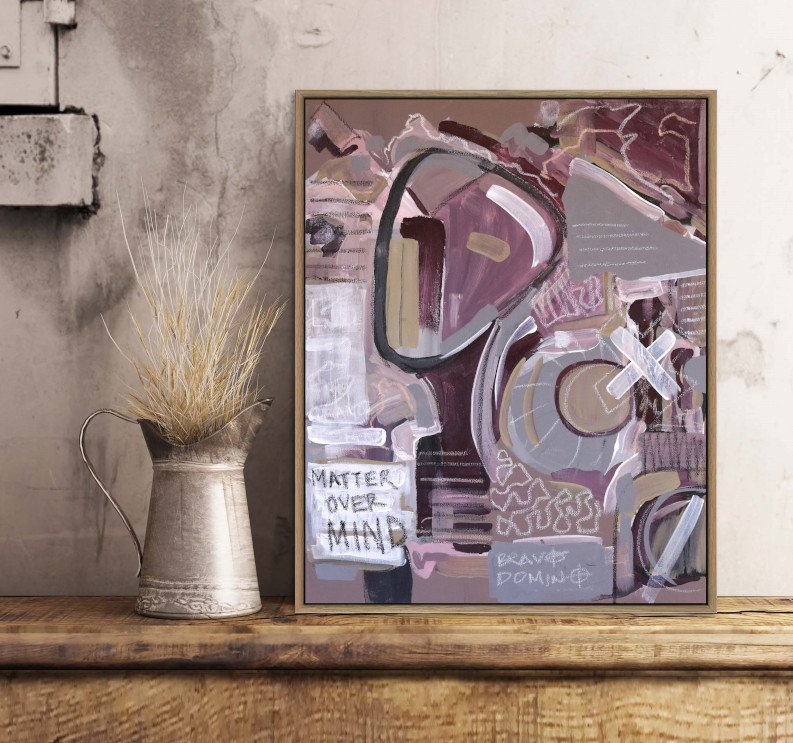 Framed neo-expressionist portrait of a face in purple and beige tones with the text 'matter over mind' in shelf with rustic decor