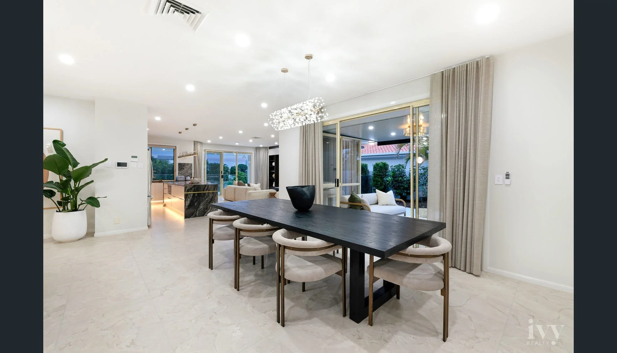 Open-concept living and dining area with large windows, modern furniture, and minimal decor.