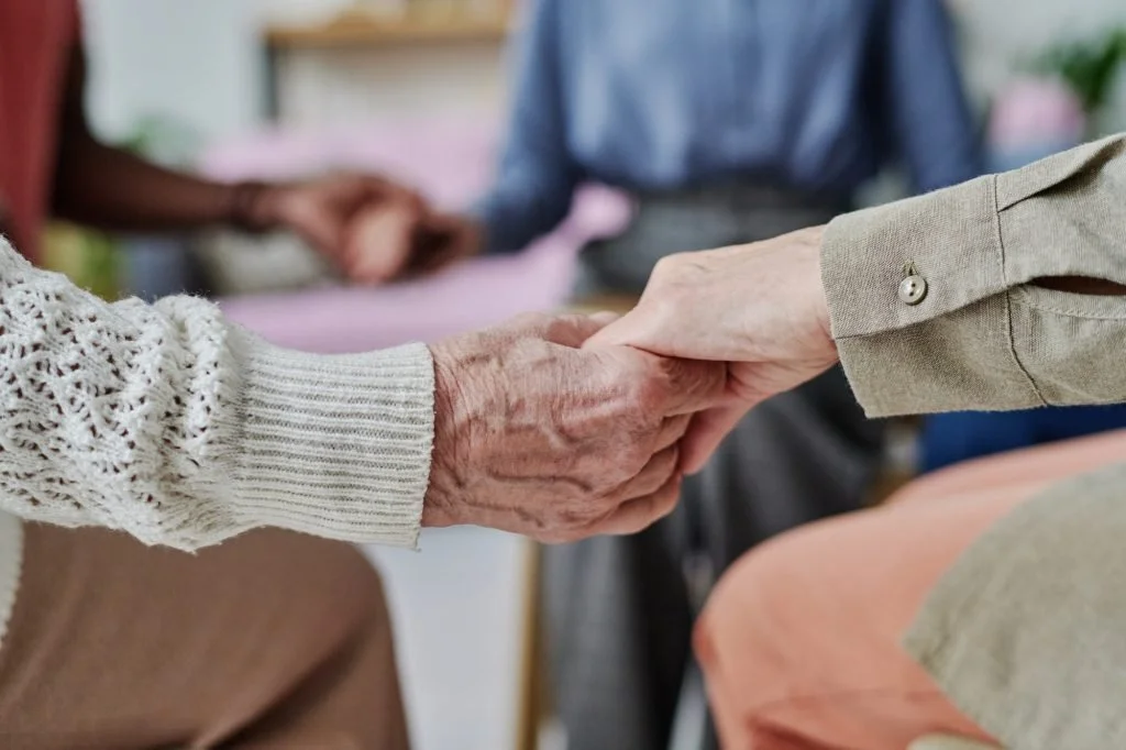 Two elderly people holding hands, showing care and support.