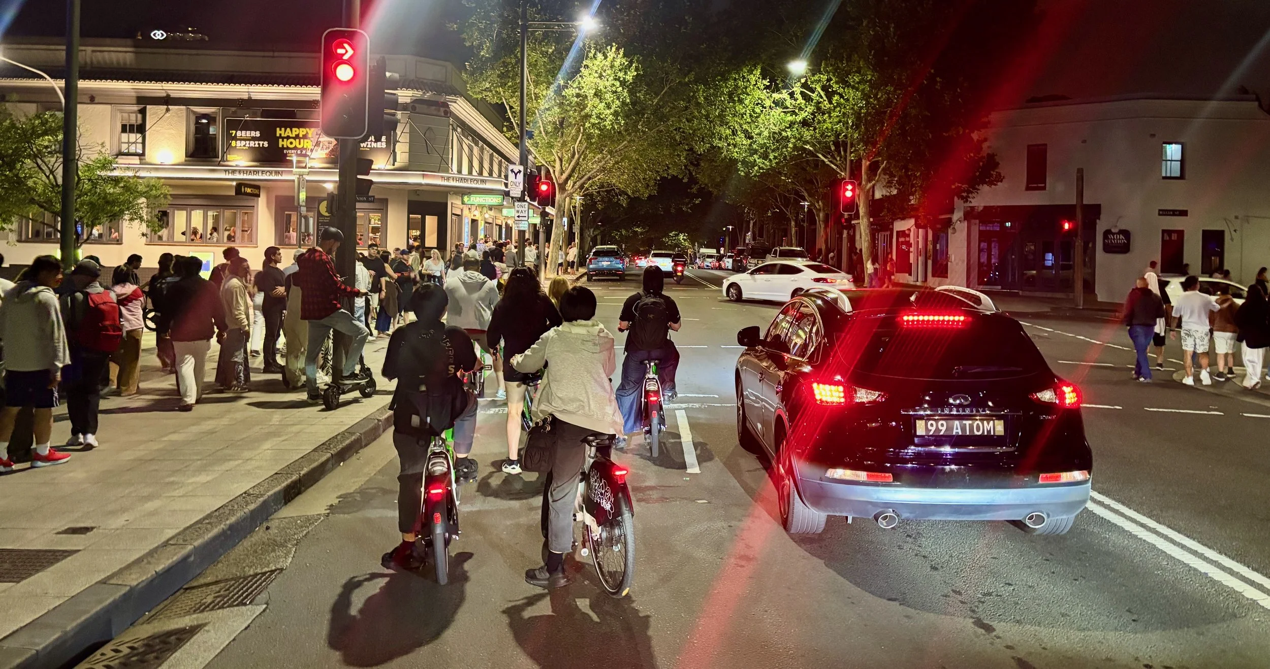 Kids riding lime bikes and lots of people walking past gridlocked vehicle traffic