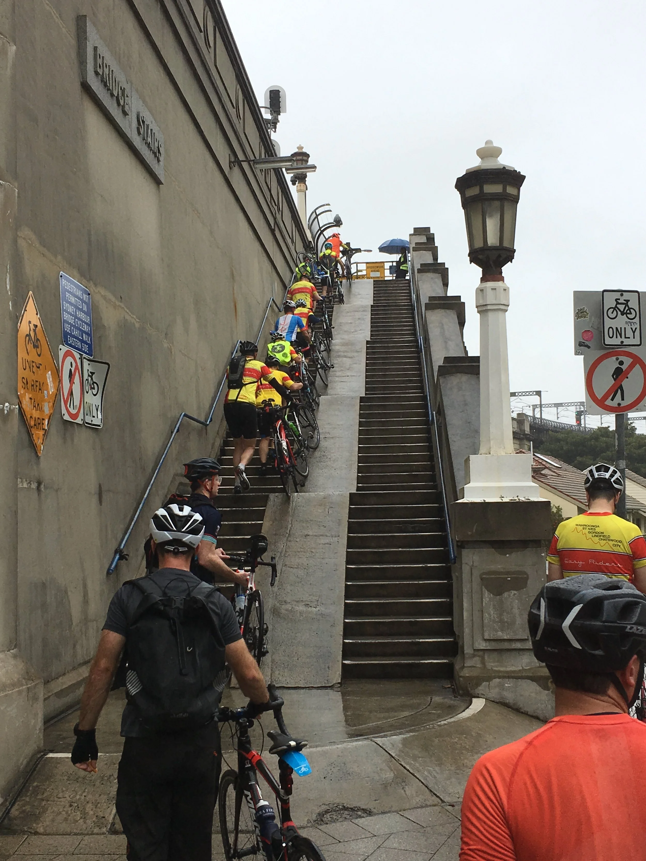 Cyclists walking up the steps in peak hour