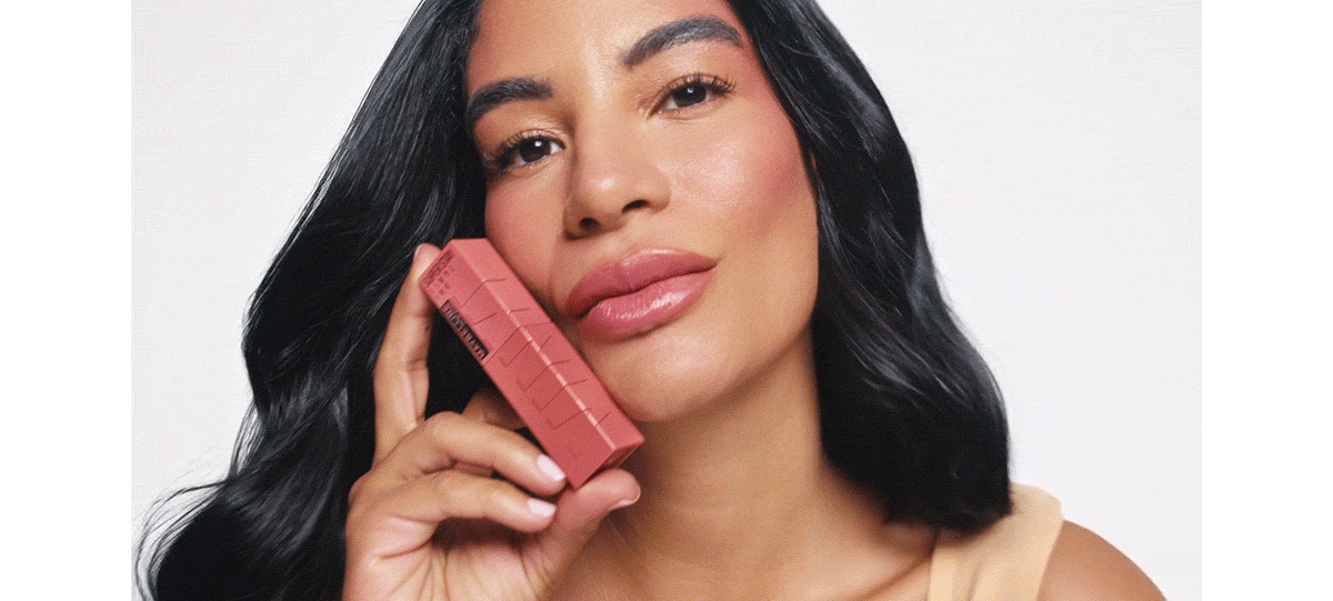 Animated beauty portrait of a dark-haired model holding rose-colored cosmetics packaging beside her face.
