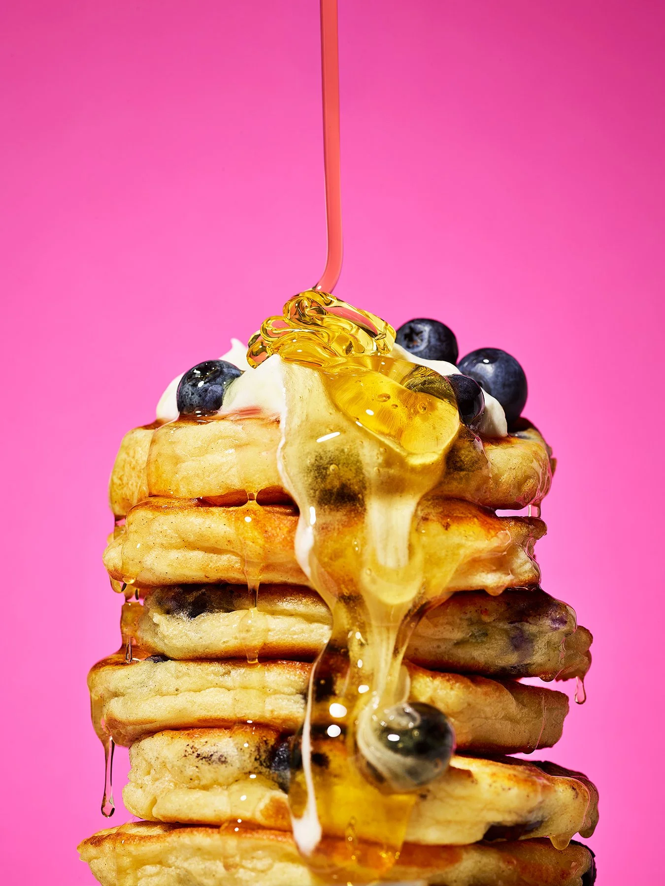 Stack of pancakes with blueberries and honey drizzled over. Photography by Danielle Wood.